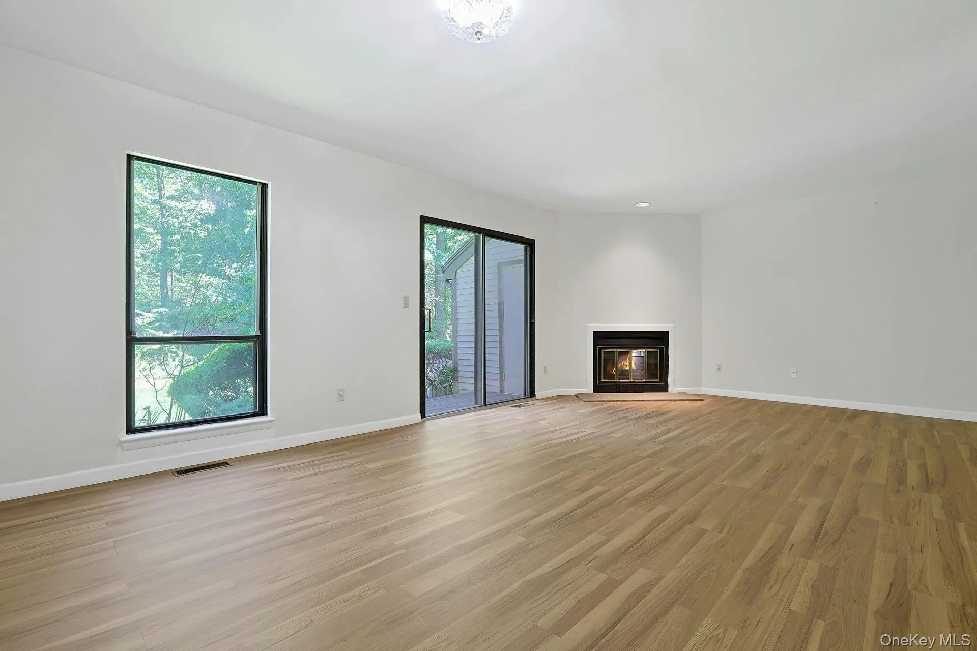 Sliding glass doors open out to the deck and rear yard, while the large window also brings much natural light, which gleams off of the new floors. Sliding glass doors open out to the deck and rear yard, while the large window also brings much natural light, which gleams off of the new floors.