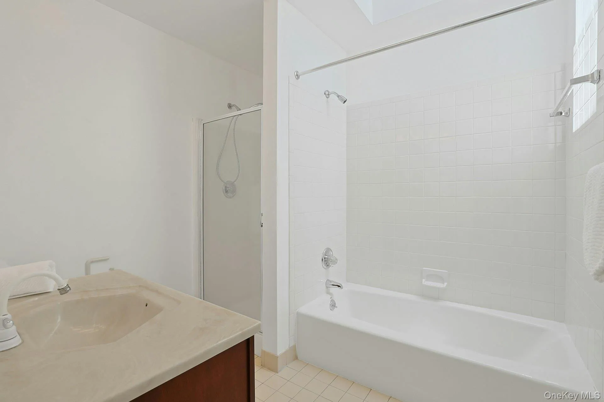 The ensuite primary bathroom features a tub with tile surround and a convenient separate glass doored shower. The ensuite primary bathroom features a tub with tile surround and a convenient separate glass doored shower.