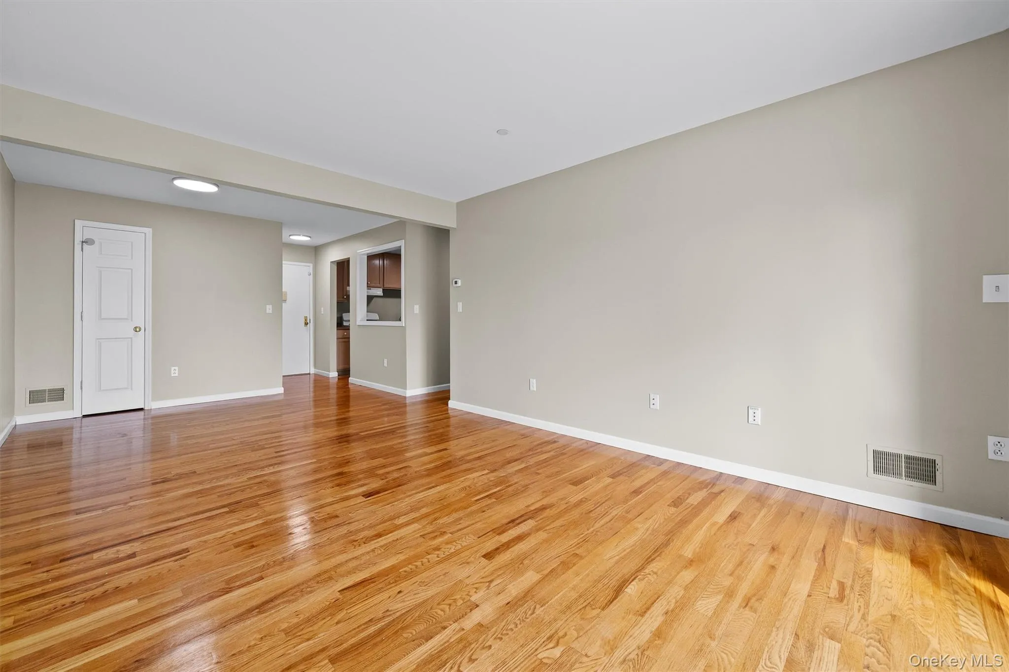 Unfurnished living room with baseboards, visible vents, and light wood-style flooring Unfurnished living room with baseboards, visible vents, and light wood-style flooring