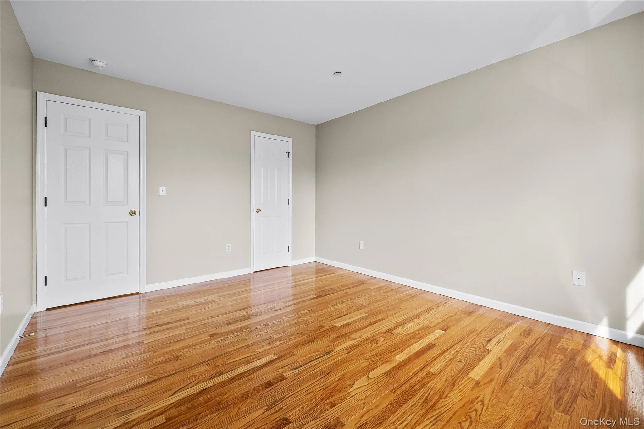 Spare room with light wood finished floors and baseboards Spare room with light wood finished floors and baseboards