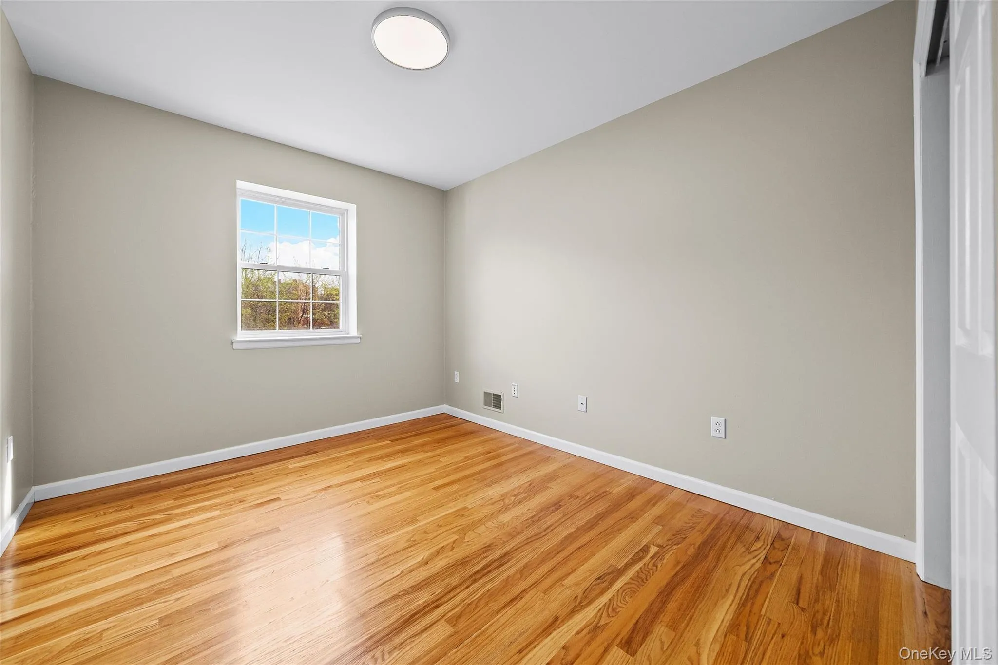 Spare room featuring wood finished floors, visible vents, and baseboards Spare room featuring wood finished floors, visible vents, and baseboards