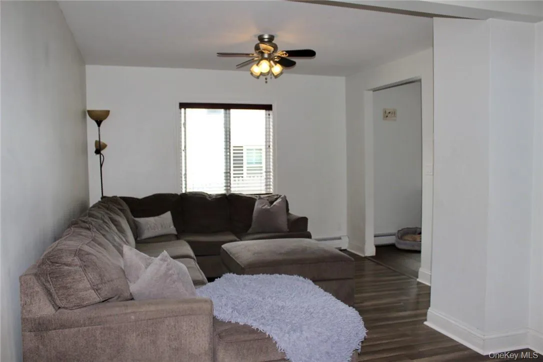 Living room with ceiling fan, baseboard heating, and dark hardwood / wood-style floors Living room with ceiling fan, baseboard heating, and dark hardwood / wood-style floors