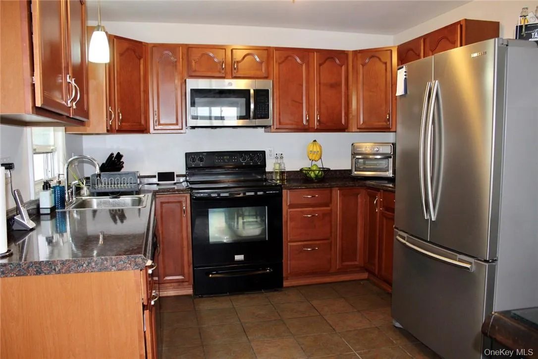 Kitchen featuring dark tile patterned floors, sink, pendant lighting, and stainless steel/Black appliances Kitchen featuring dark tile patterned floors, sink, pendant lighting, and stainless steel/Black appliances