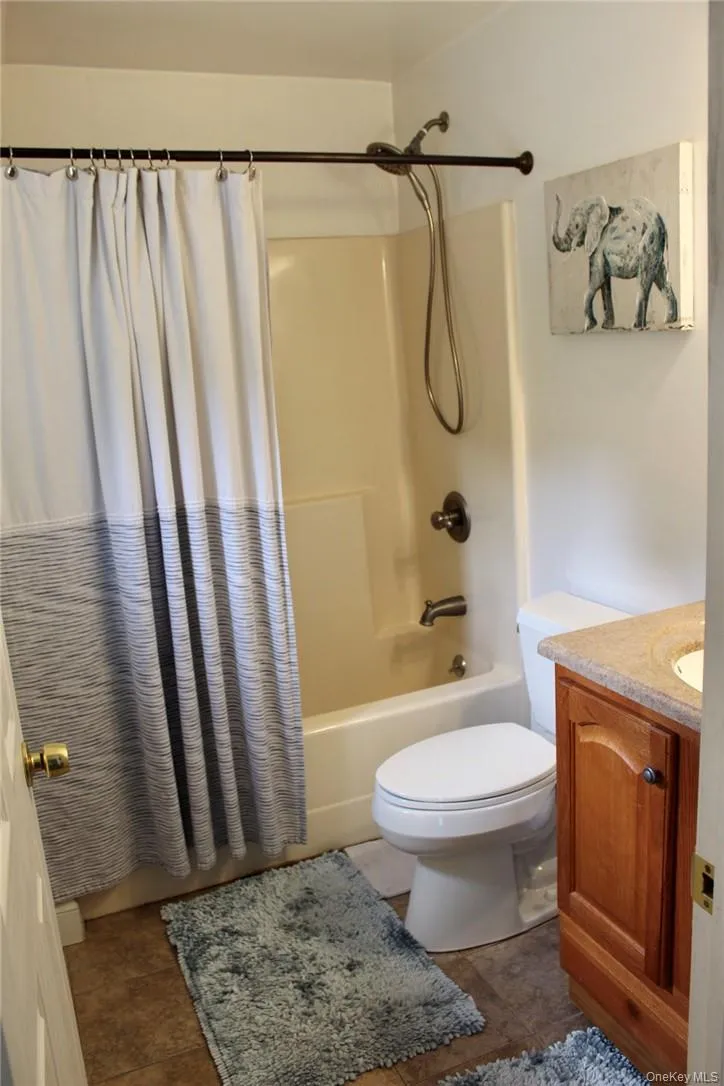 Full bathroom with shower / tub combo, tile patterned flooring, vanity, and toilet Full bathroom with shower / tub combo, tile patterned flooring, vanity, and toilet