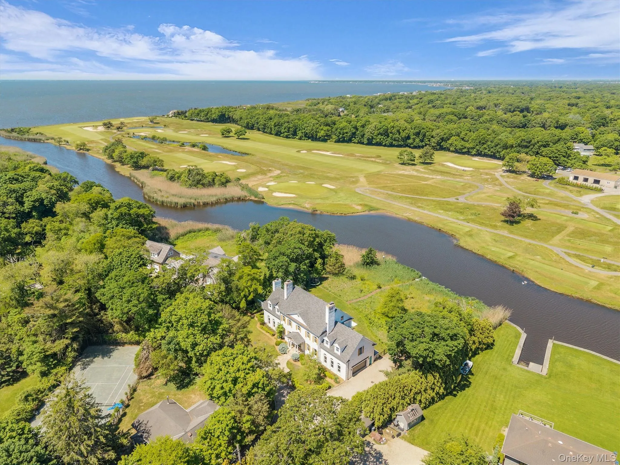Waterfront property featuring a white multi-story residence with a pool, expansive lawn, and a private dock. Views of golf course and Bellport Bay Waterfront property featuring a white multi-story residence with a pool, expansive lawn, and a private dock. Views of golf course and Bellport Bay