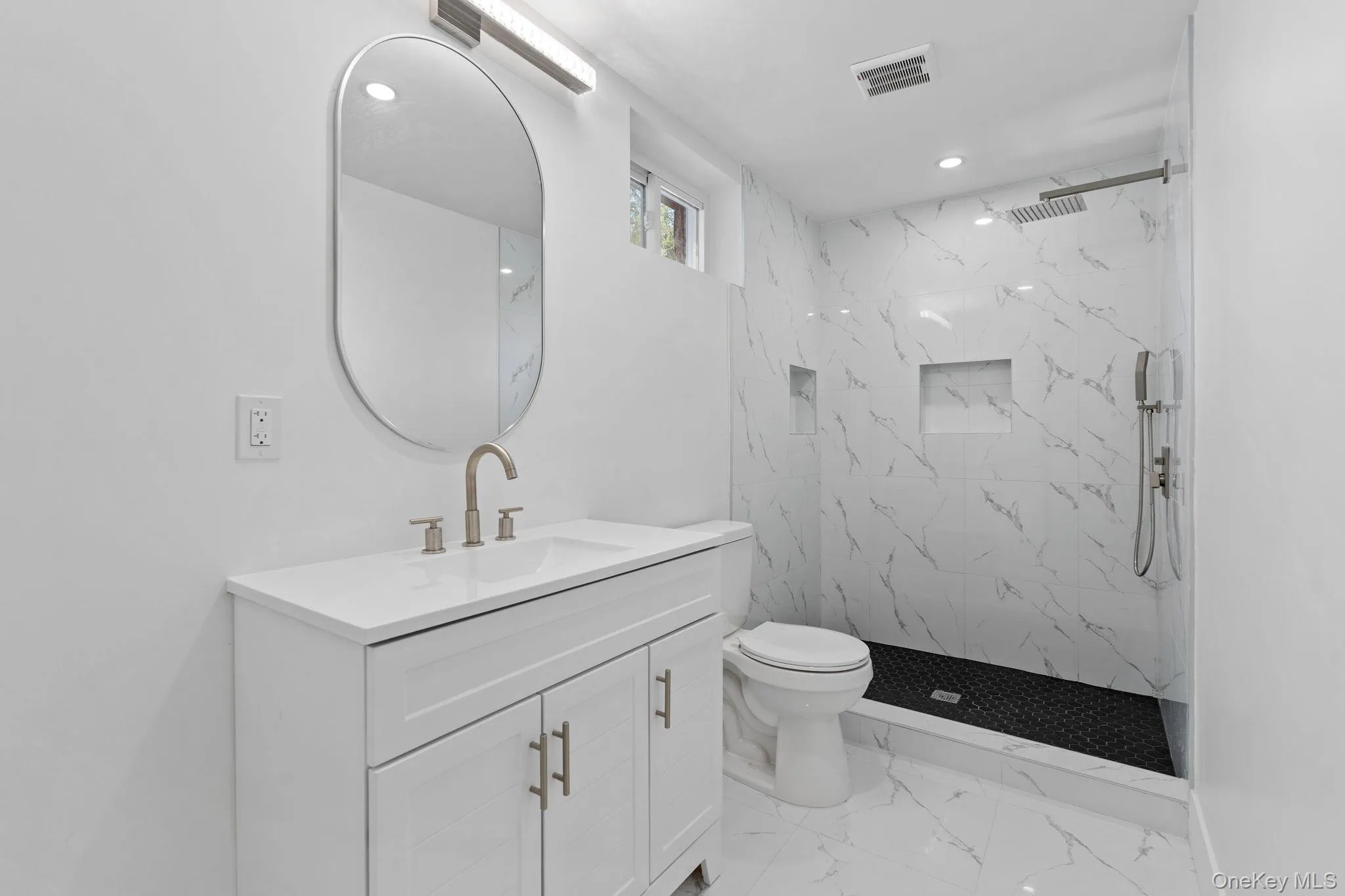 Full bathroom with vanity, a marble finish shower, light marble finish floors, and recessed lighting Full bathroom with vanity, a marble finish shower, light marble finish floors, and recessed lighting