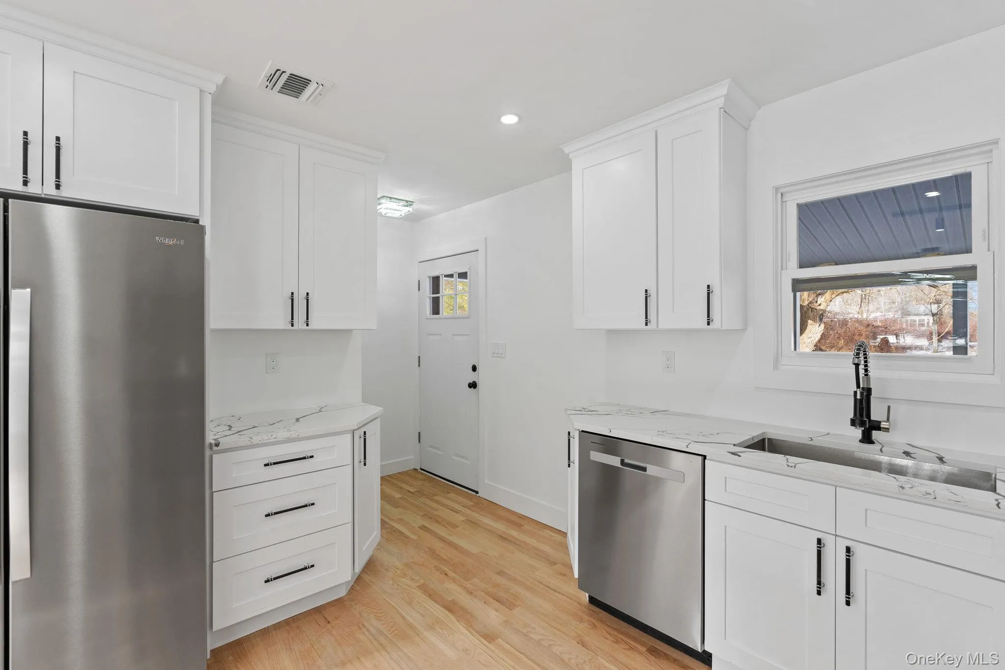Kitchen featuring stainless steel appliances, white cabinets, light stone counters, recessed lighting, and light wood finished floors Kitchen featuring stainless steel appliances, white cabinets, light stone counters, recessed lighting, and light wood finished floors
