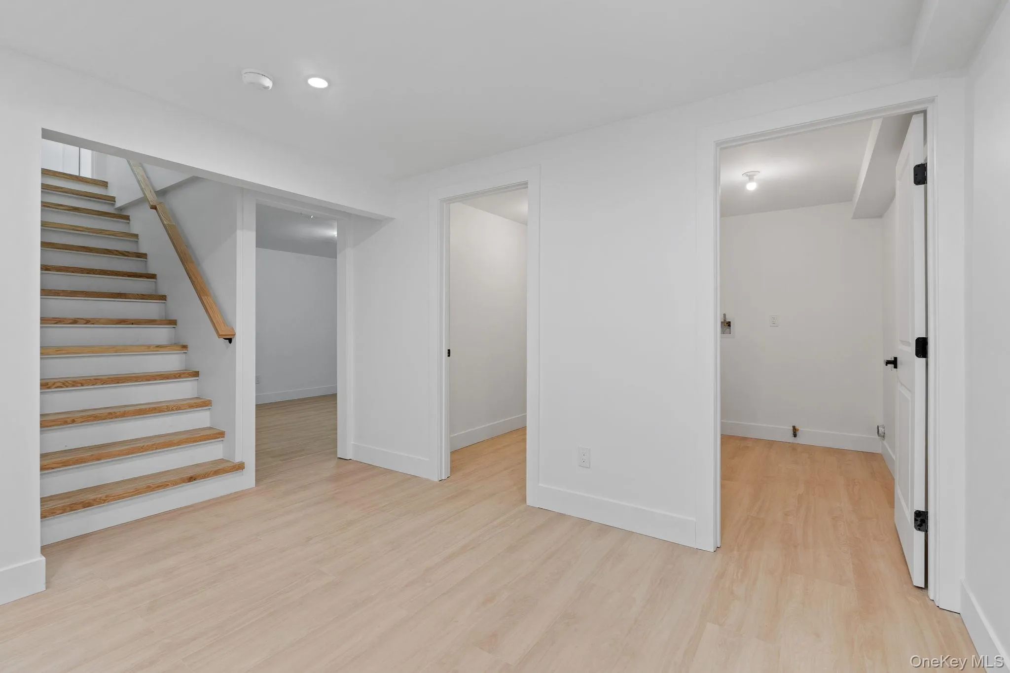 Basement featuring light wood-type flooring and stairway Basement featuring light wood-type flooring and stairway