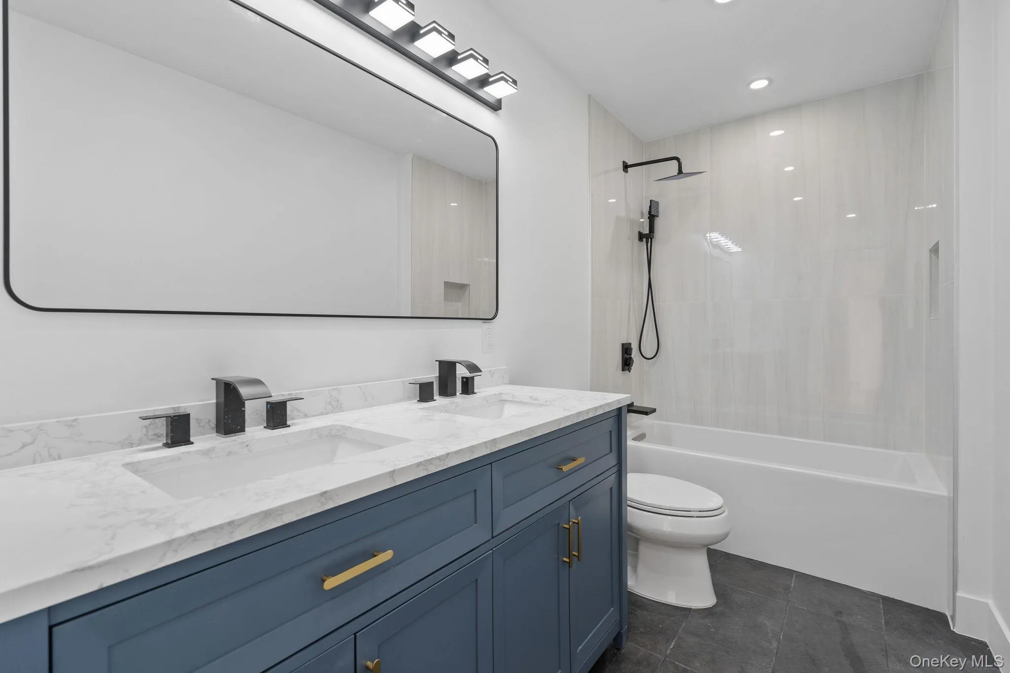 Full bathroom featuring double vanity, shower / bathtub combination, recessed lighting, and dark tile patterned flooring Full bathroom featuring double vanity, shower / bathtub combination, recessed lighting, and dark tile patterned flooring