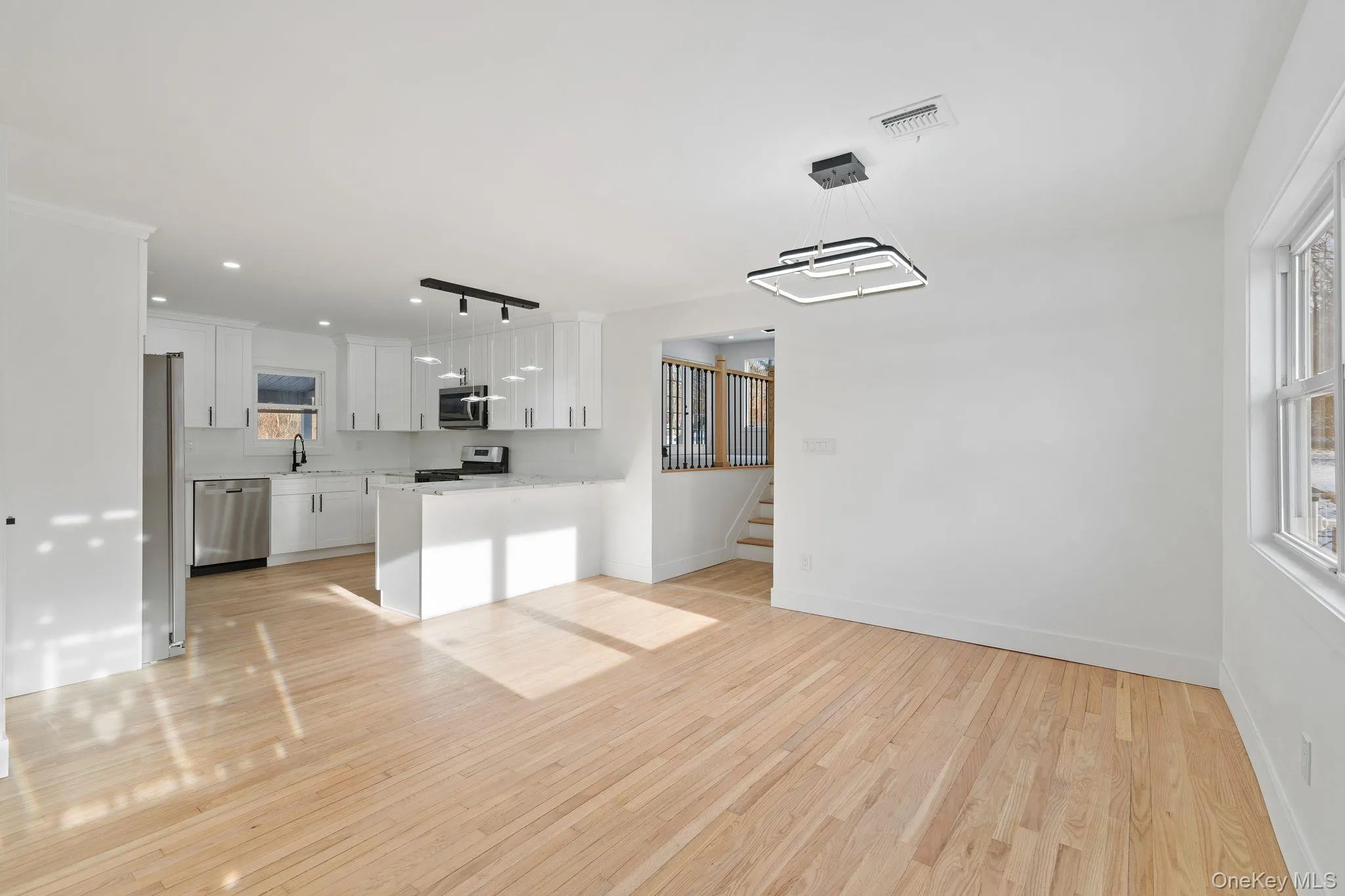 Unfurnished living room featuring light wood-type flooring, recessed lighting, and stairs Unfurnished living room featuring light wood-type flooring, recessed lighting, and stairs