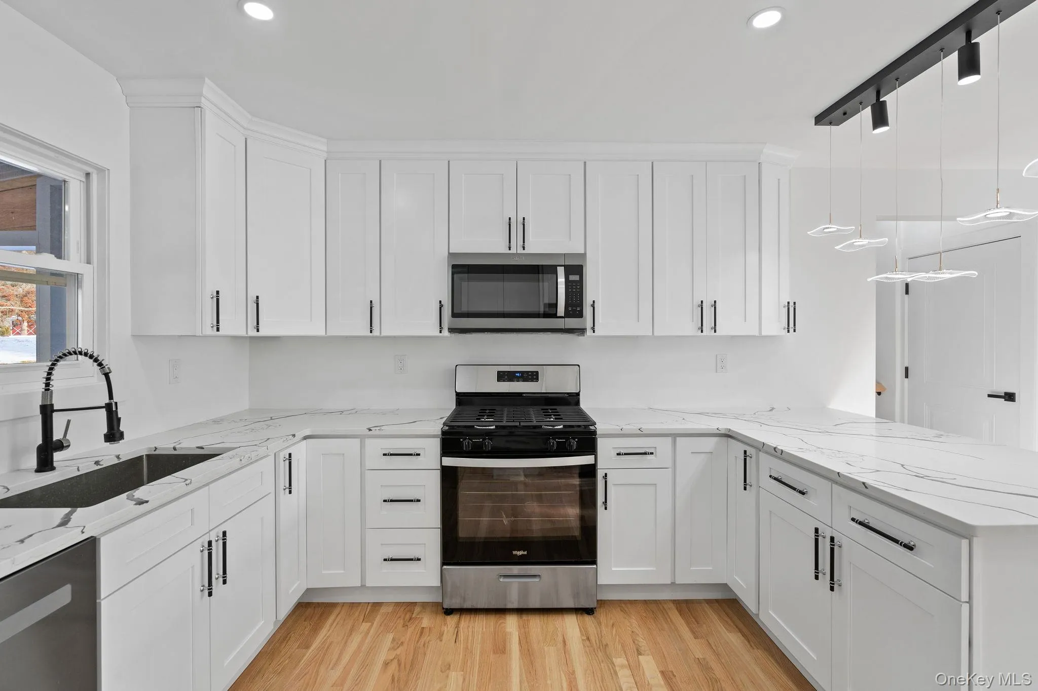 Kitchen with stainless steel appliances, light stone counters, pendant lighting, white cabinetry, and a peninsula Kitchen with stainless steel appliances, light stone counters, pendant lighting, white cabinetry, and a peninsula