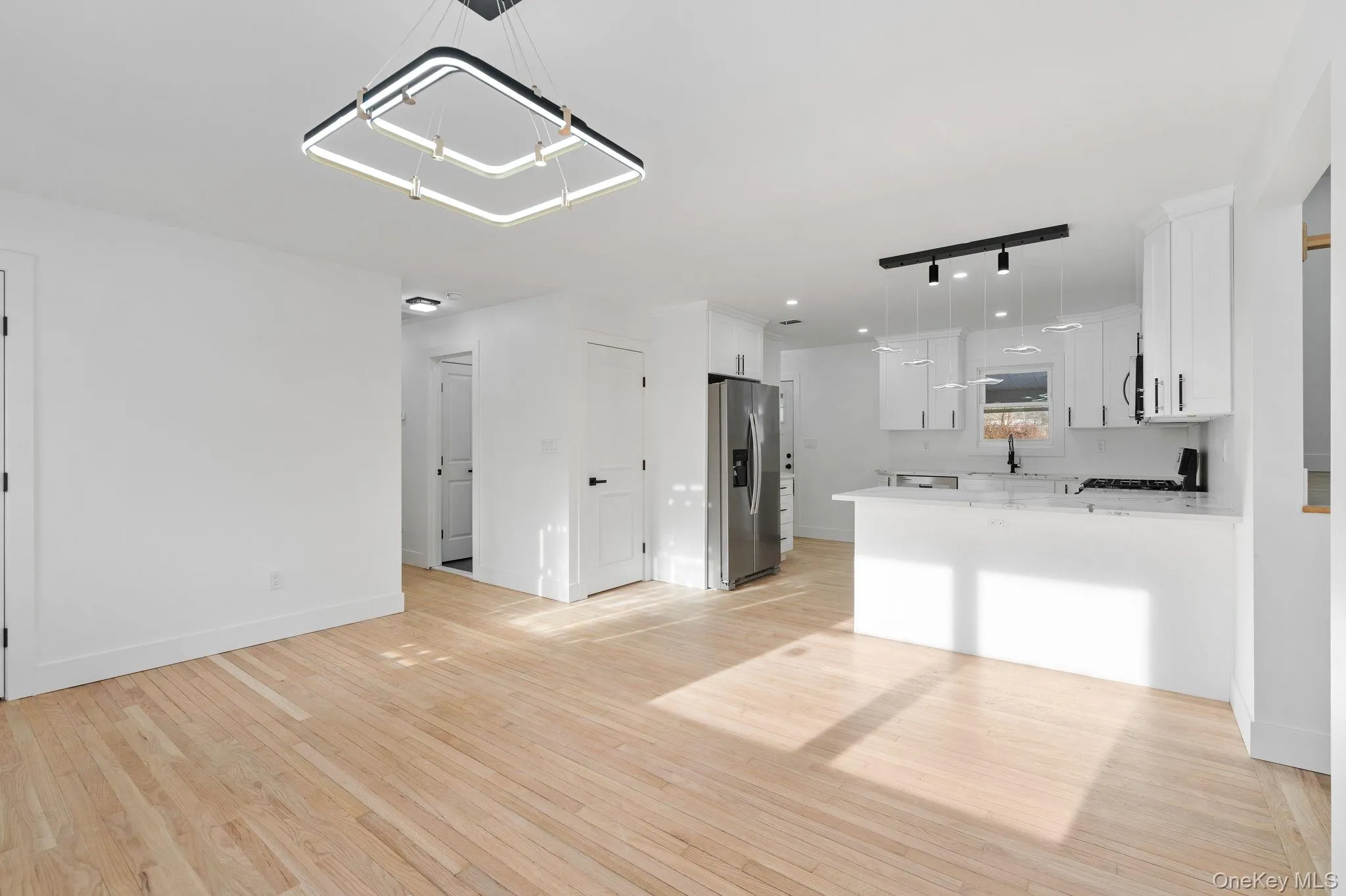 Unfurnished living room with light wood-style floors and track lighting Unfurnished living room with light wood-style floors and track lighting