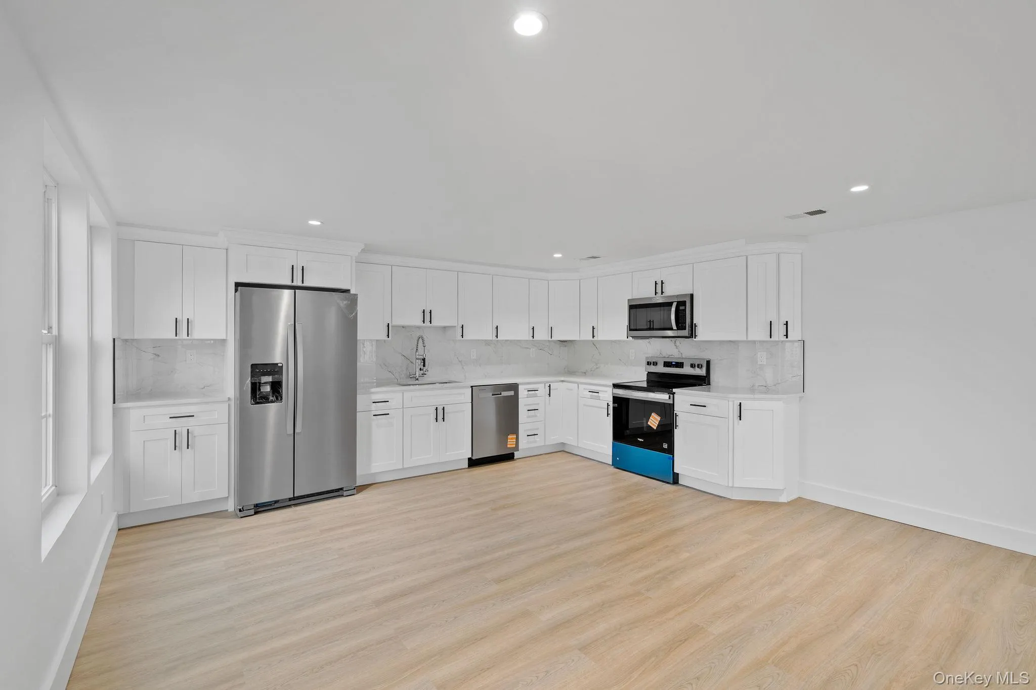 Kitchen with stainless steel appliances, white cabinetry, light wood-type flooring, tasteful backsplash, and recessed lighting Kitchen with stainless steel appliances, white cabinetry, light wood-type flooring, tasteful backsplash, and recessed lighting