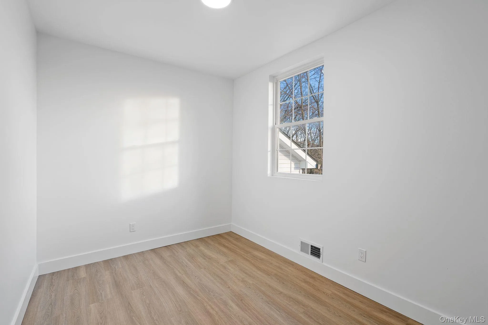 Empty room with light wood-type flooring and baseboards Empty room with light wood-type flooring and baseboards