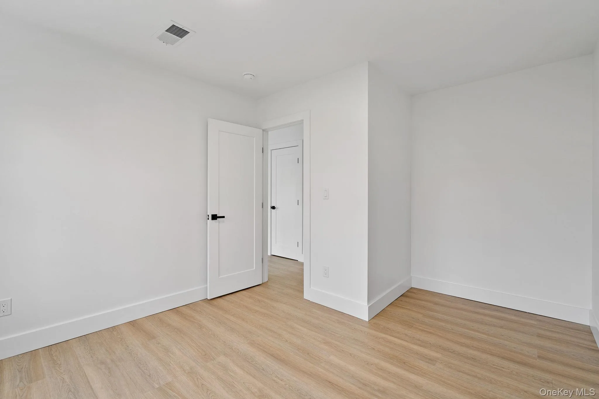 Unfurnished room with light wood-style floors and baseboards Unfurnished room with light wood-style floors and baseboards