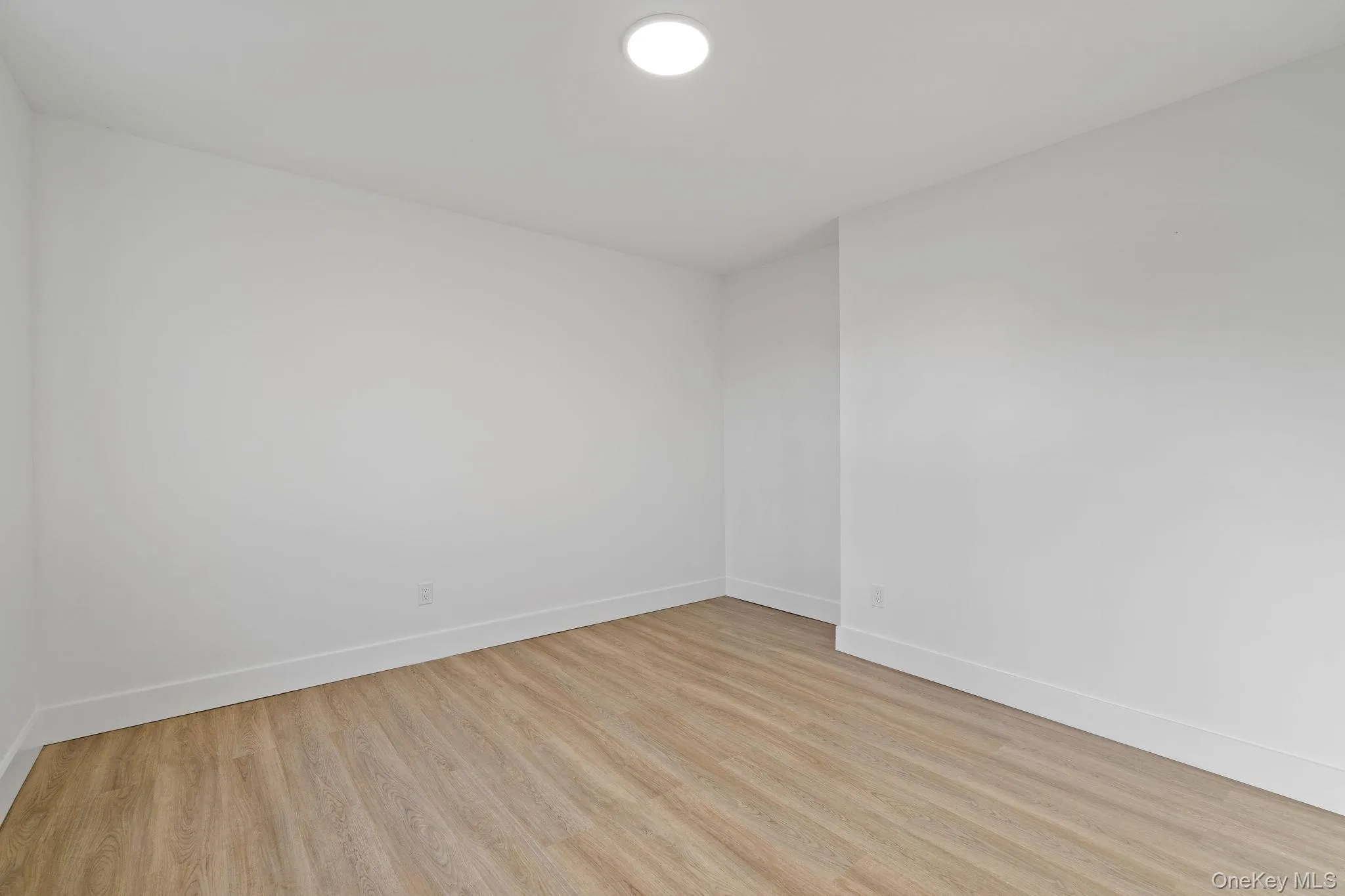 Empty room with baseboards and light wood finished floors Empty room with baseboards and light wood finished floors