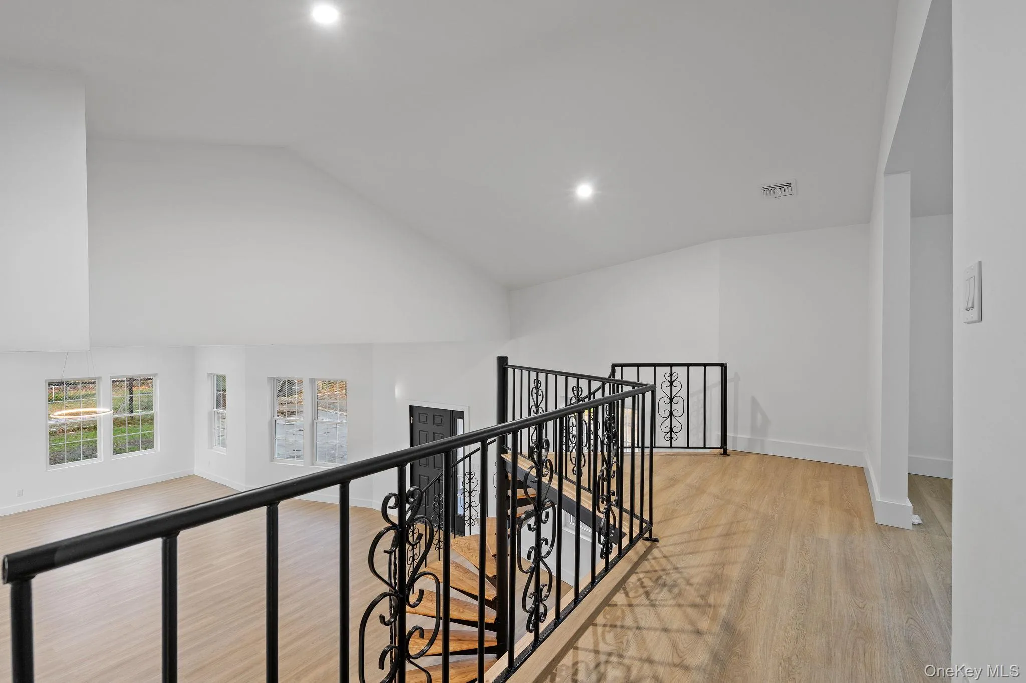 Hallway featuring light wood-type flooring, an upstairs landing, recessed lighting, and high vaulted ceiling Hallway featuring light wood-type flooring, an upstairs landing, recessed lighting, and high vaulted ceiling