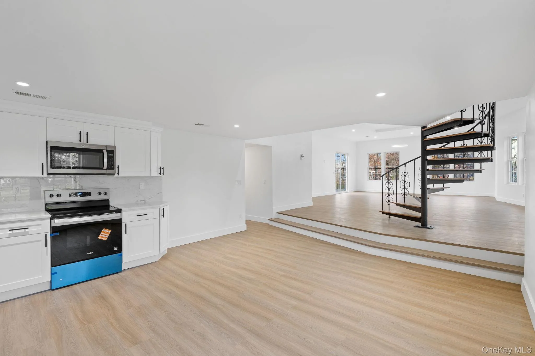 Kitchen featuring stainless steel appliances, light wood-style flooring, white cabinetry, recessed lighting, and backsplash Kitchen featuring stainless steel appliances, light wood-style flooring, white cabinetry, recessed lighting, and backsplash