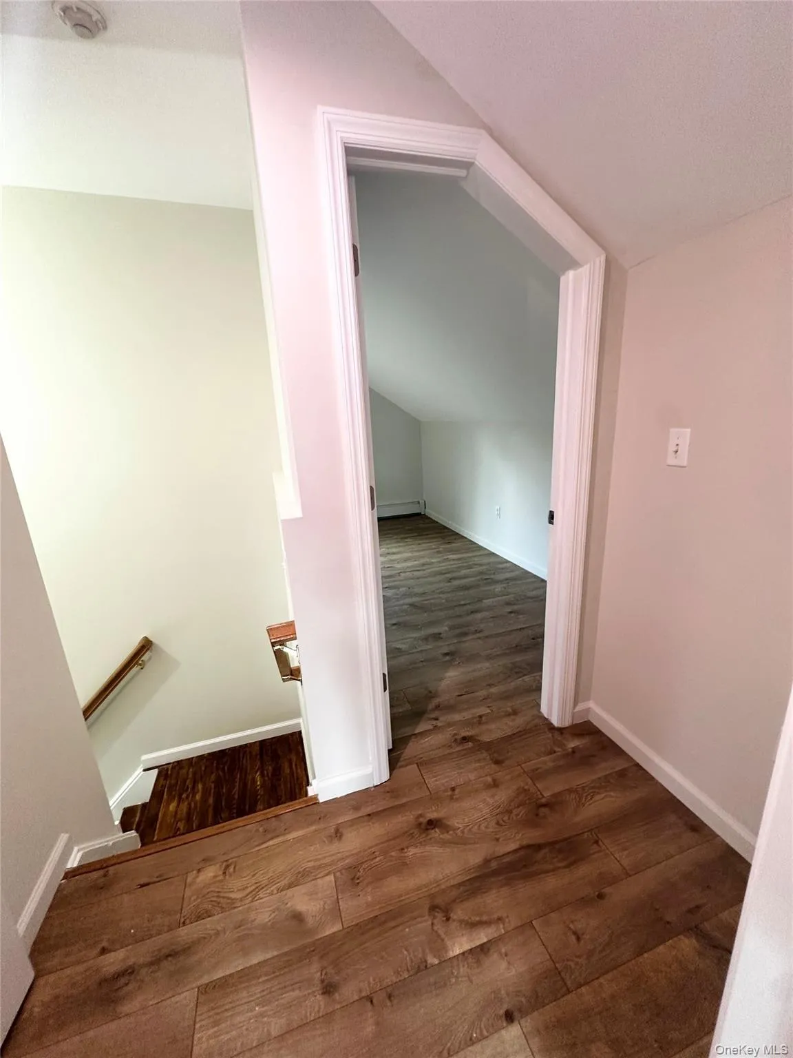 Hallway with an upstairs landing and dark wood finished floors Hallway with an upstairs landing and dark wood finished floors
