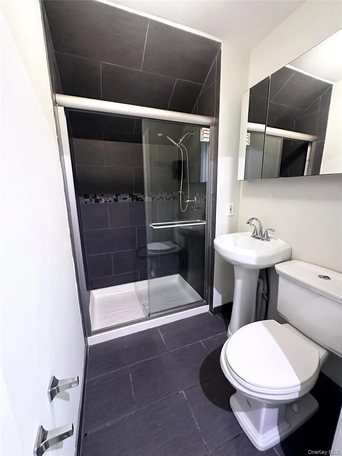 Full bath featuring a shower stall and dark tile patterned flooring Full bath featuring a shower stall and dark tile patterned flooring