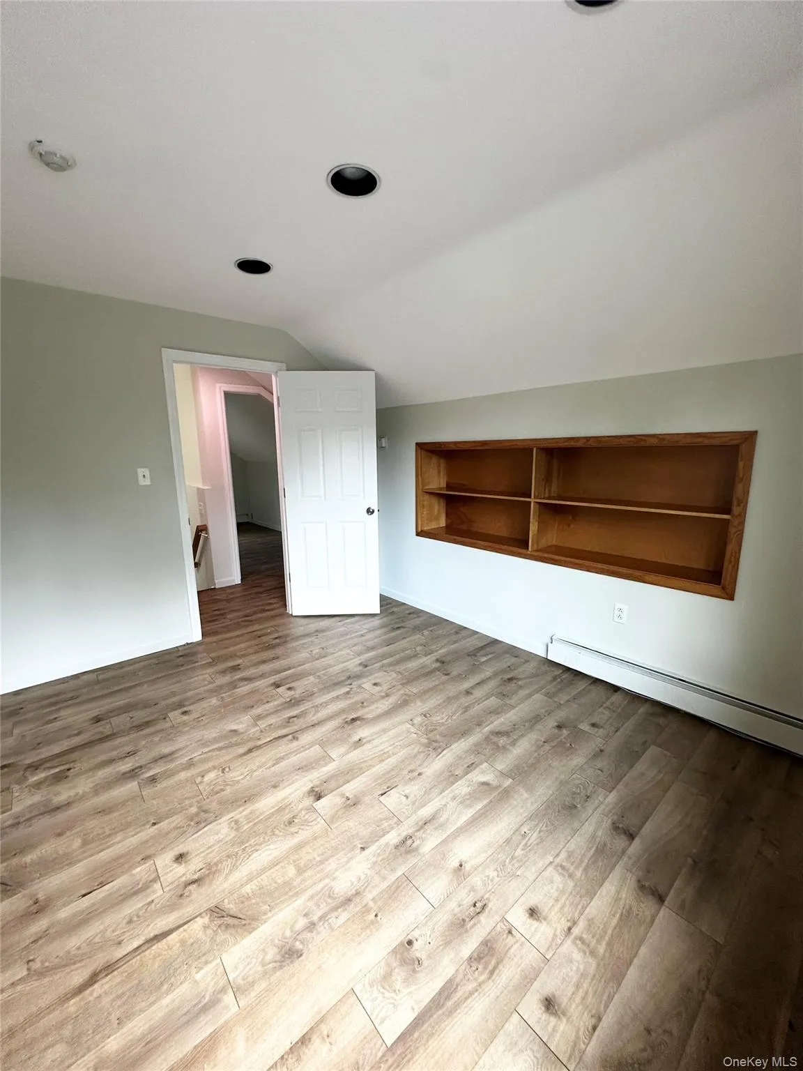 Bonus room with a baseboard heating unit, vaulted ceiling, and light wood-style floors Bonus room with a baseboard heating unit, vaulted ceiling, and light wood-style floors