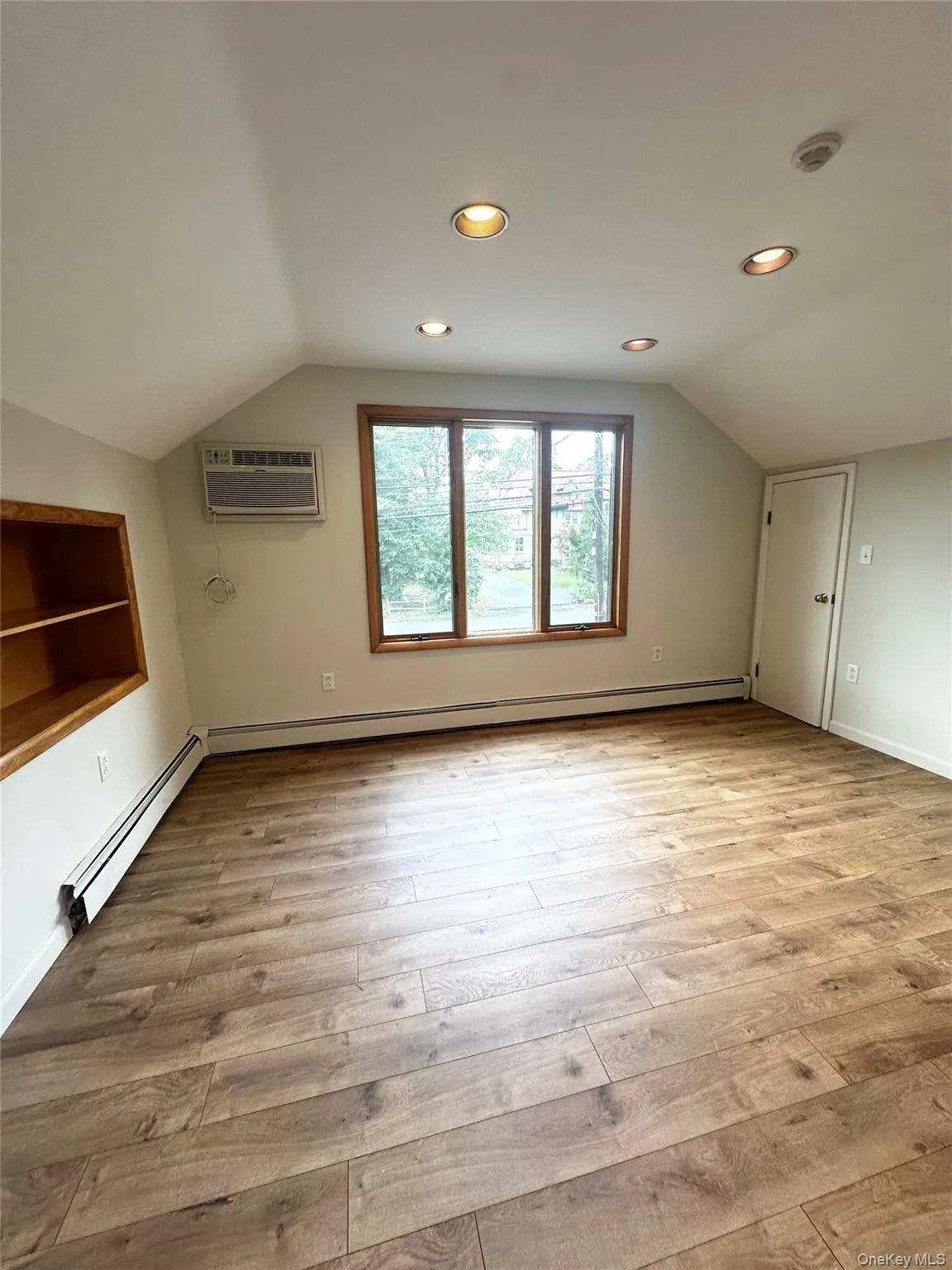 Bonus room with vaulted ceiling, light wood-style flooring, recessed lighting, baseboard heating, and a wall mounted air conditioner Bonus room with vaulted ceiling, light wood-style flooring, recessed lighting, baseboard heating, and a wall mounted air conditioner