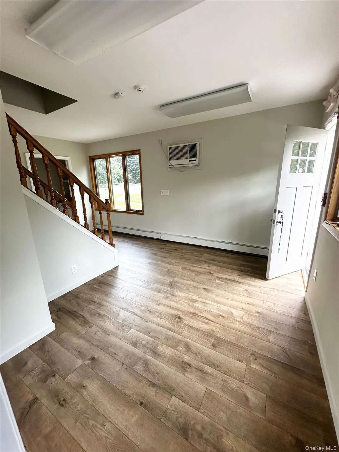 Foyer entrance with stairs, light wood-style flooring, a baseboard heating unit, and a wall mounted air conditioner Foyer entrance with stairs, light wood-style flooring, a baseboard heating unit, and a wall mounted air conditioner