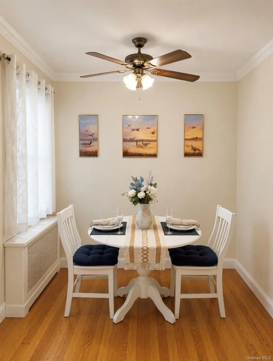 Dining area featuring wood-finish flooring, crown molding, and a ceiling fan with integrated lighting Dining area featuring wood-finish flooring, crown molding, and a ceiling fan with integrated lighting