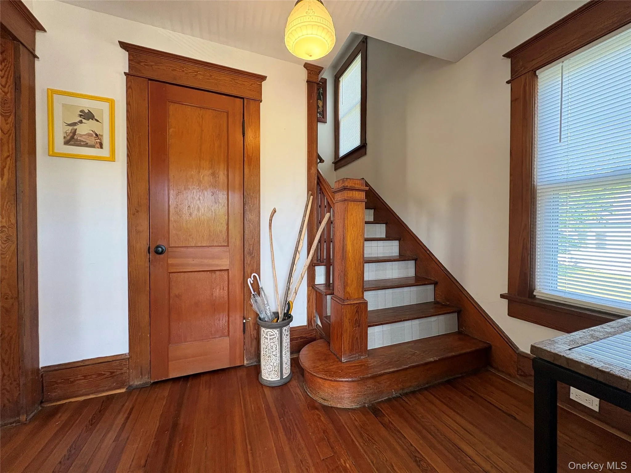 Hardwood flooring and staircase featuring rich wood finishes, classic trim work, and a paneled door Hardwood flooring and staircase featuring rich wood finishes, classic trim work, and a paneled door