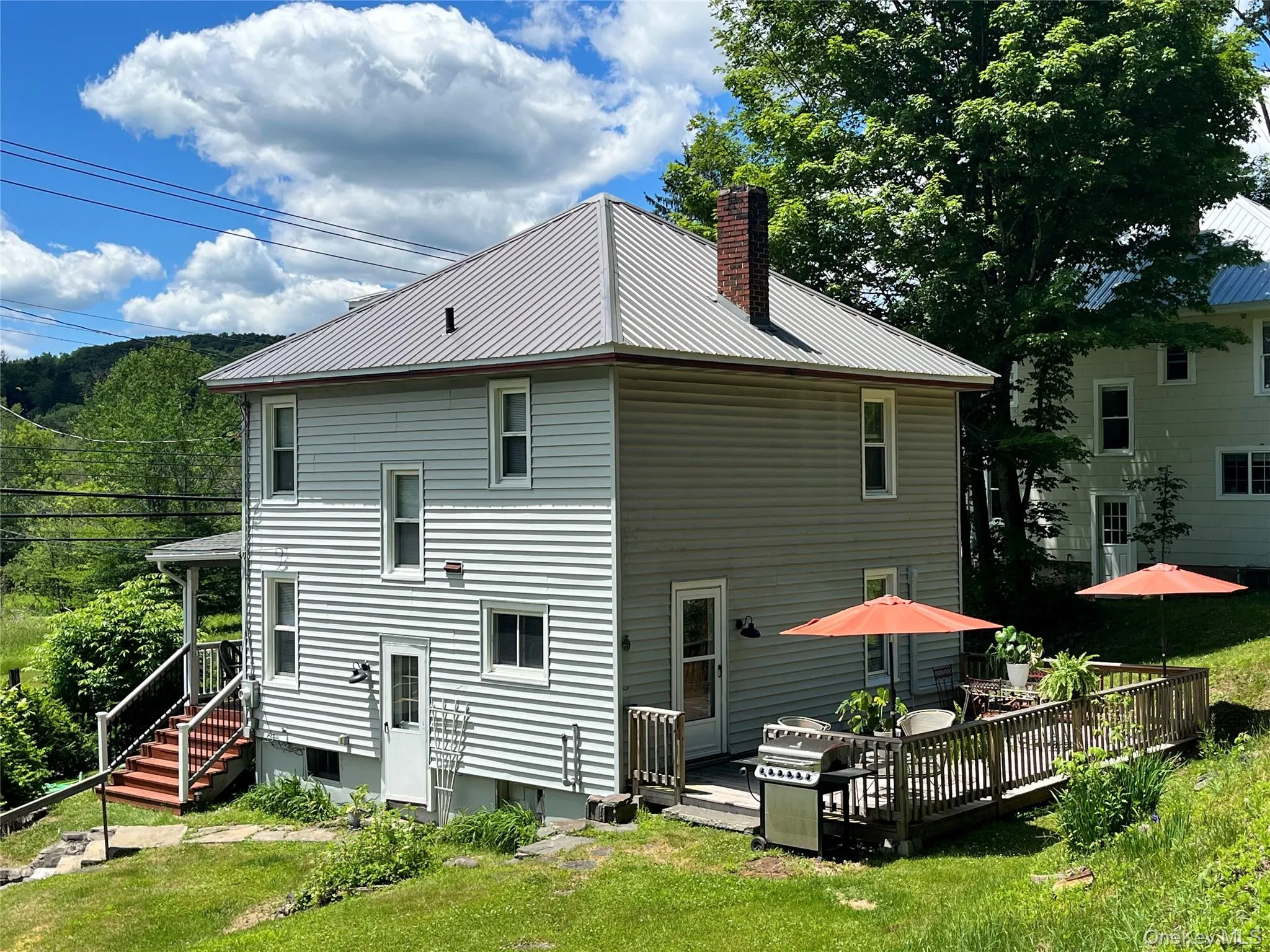 Two-story residence featuring light-colored horizontal siding and a gray metal roof Two-story residence featuring light-colored horizontal siding and a gray metal roof