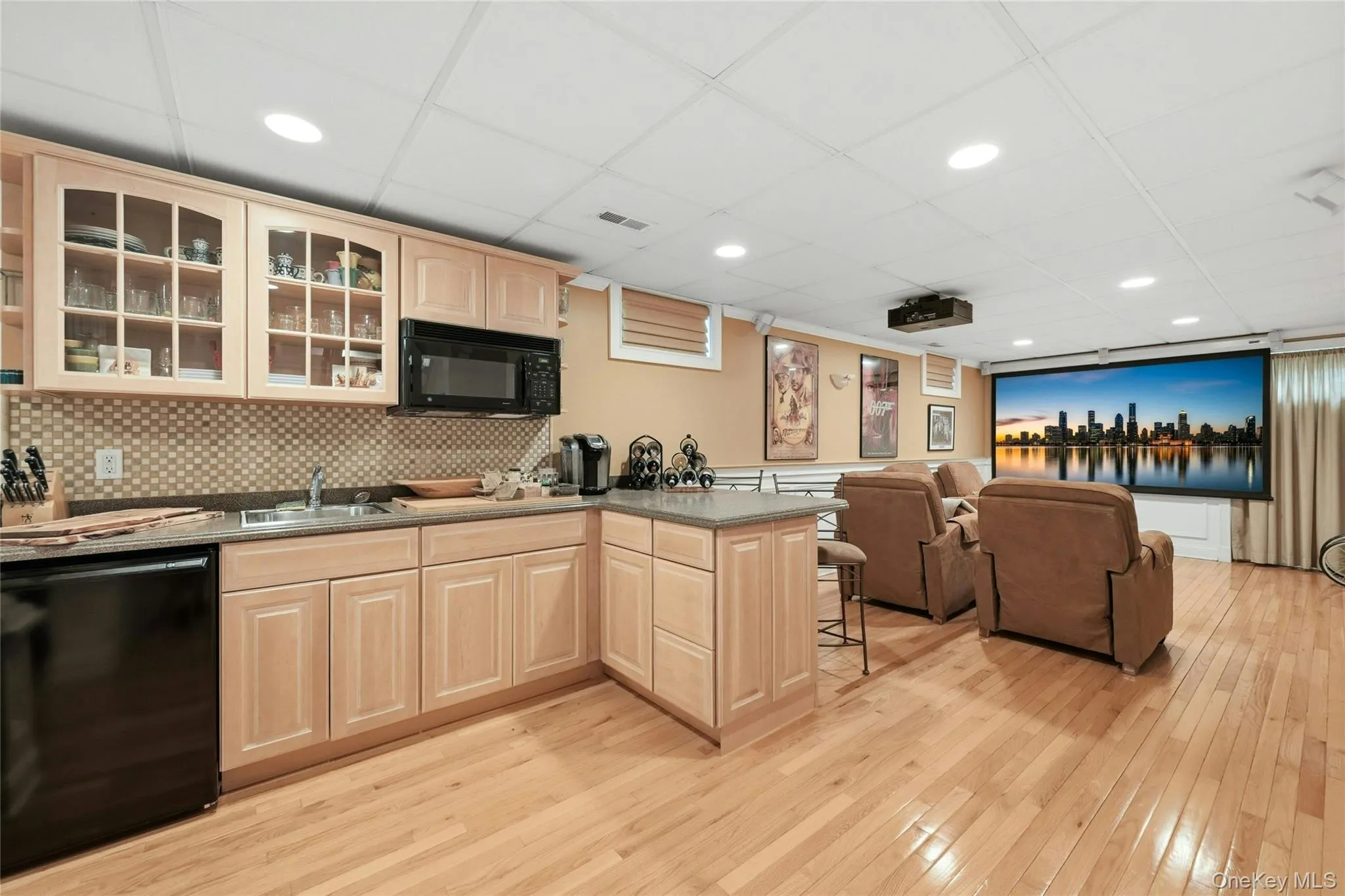 The Spectacular Expansive Lower Level Media Room Is The Epitome Of Entertaining & Recreation Space..Offering A Movie Projector, Screen, 5.1 Bose Surround System, Entertainment Styled Box Paneled/Wainscoted Walls With Custom Moldings, Built In Bench/Seating Spaces, An Oversized Stunning Custom Wet Bar With Maple Cabinetry, Glass Doors, Corian Countertops With Built In Barstool Area, Accent Tiled Backsplash, Refrigerator & Built In Microwave Oven, Hardwood Floors Throughout, Recessed Lighting, All Custom Details, And Dual Columns To A Separate Exercise Room. The Spectacular Expansive Lower Level Media Room Is The Epitome Of Entertaining & Recreation Space..Offering A Movie Projector, Screen, 5.1 Bose Surround System, Entertainment Styled Box Paneled/Wainscoted Walls With Custom Moldings, Built In Bench/Seating Spaces, An Oversized Stunning Custom Wet Bar With Maple Cabinetry, Glass Doors, Corian Countertops With Built In Barstool Area, Accent Tiled Backsplash, Refrigerator & Built In Microwave Oven, Hardwood Floors Throughout, Recessed Lighting, All Custom Details, And Dual Columns To A Separate Exercise Room.