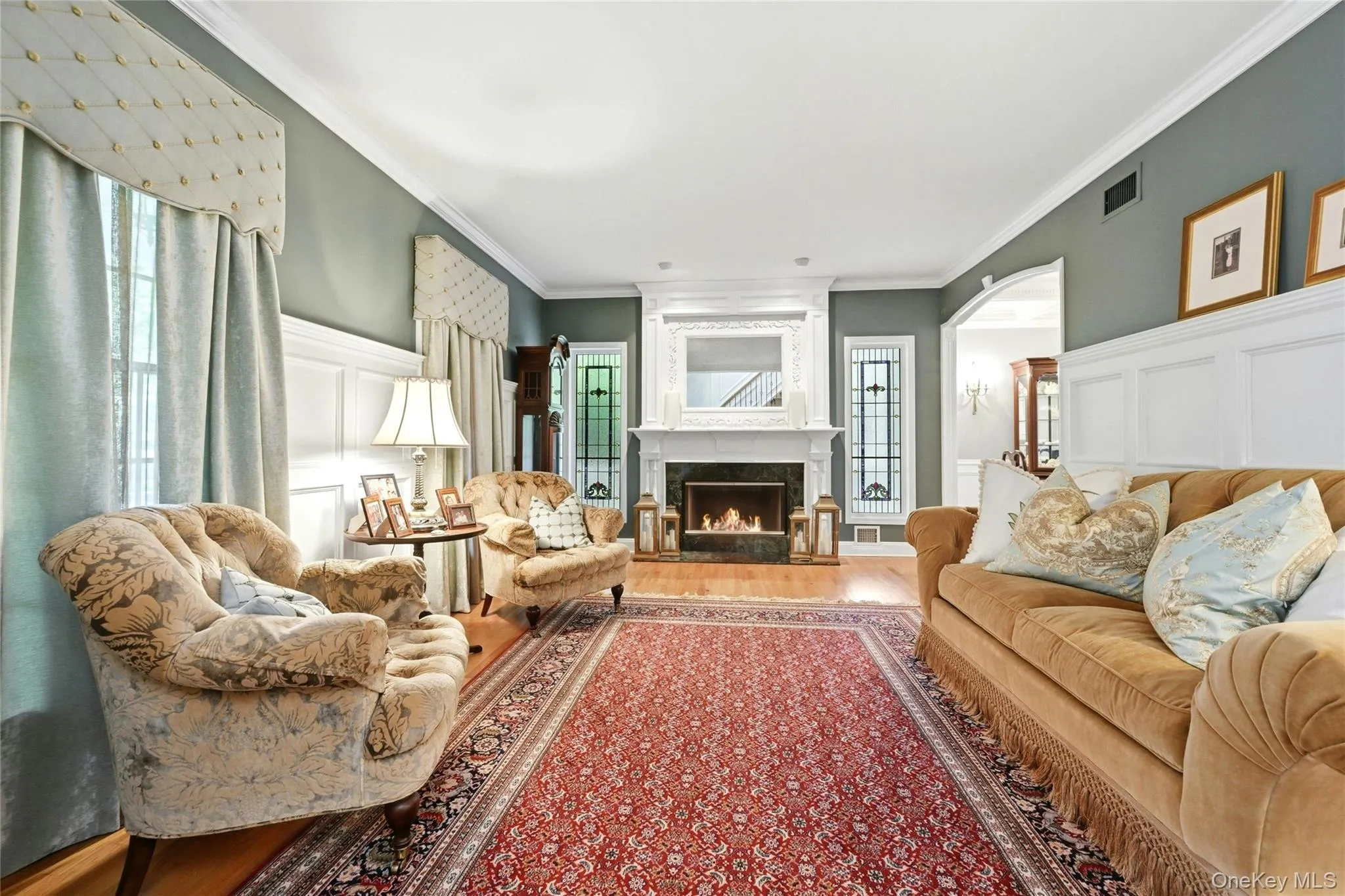 The Elegant, Stunning Formal Living Room Offers A Two Columned Entrance, Spectacular 6' Box Paneled/Wainscoted Walls, Magnificent Focal Point Wood Burning Fireplace With A Custom Floor To Ceiling Wood Mantel, Marble Surround & Base Flanked By Exquisite Stained Glass Windows, 9' Ceilings With Oversized Andersen Windows, Custom Moldings, Hardwood Floors & A Beautiful Custom Archway (Also With Beautiful Moldings/Trims) Into The Formal Dining Room. The Elegant, Stunning Formal Living Room Offers A Two Columned Entrance, Spectacular 6' Box Paneled/Wainscoted Walls, Magnificent Focal Point Wood Burning Fireplace With A Custom Floor To Ceiling Wood Mantel, Marble Surround & Base Flanked By Exquisite Stained Glass Windows, 9' Ceilings With Oversized Andersen Windows, Custom Moldings, Hardwood Floors & A Beautiful Custom Archway (Also With Beautiful Moldings/Trims) Into The Formal Dining Room.