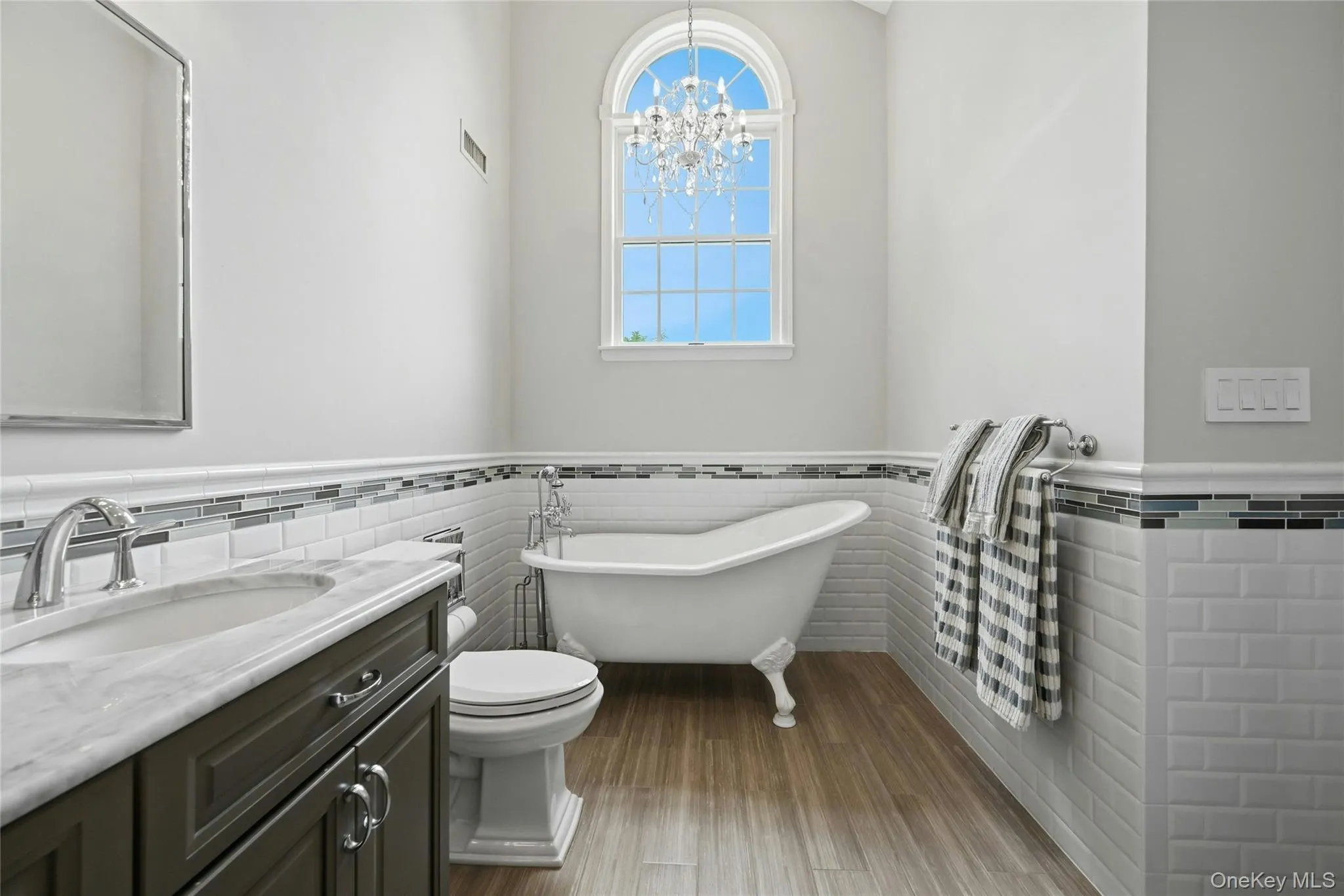 The Primary Bathroom Is A Page Out Of Architectural Digest Magazine - A Stunning Free Standing Antique Style Tub With High End Fixtures, Soaring Ceilings With An Accent Circle Topped Window & Chandelier, Oversized Custom Shower With Classic Subway Tiled Walls & Wraparound Frameless Glass Doors (Original Walls Removed When The Bathroom Was Redesigned), All Subway Tiled Walls With Decorative Borders, Custom Dual Sink Marble Topped Vanity, Porcelain Plank Tiled Floors & All Upgraded Fixtures...A True Showplace. The Primary Bathroom Is A Page Out Of Architectural Digest Magazine - A Stunning Free Standing Antique Style Tub With High End Fixtures, Soaring Ceilings With An Accent Circle Topped Window & Chandelier, Oversized Custom Shower With Classic Subway Tiled Walls & Wraparound Frameless Glass Doors (Original Walls Removed When The Bathroom Was Redesigned), All Subway Tiled Walls With Decorative Borders, Custom Dual Sink Marble Topped Vanity, Porcelain Plank Tiled Floors & All Upgraded Fixtures...A True Showplace.