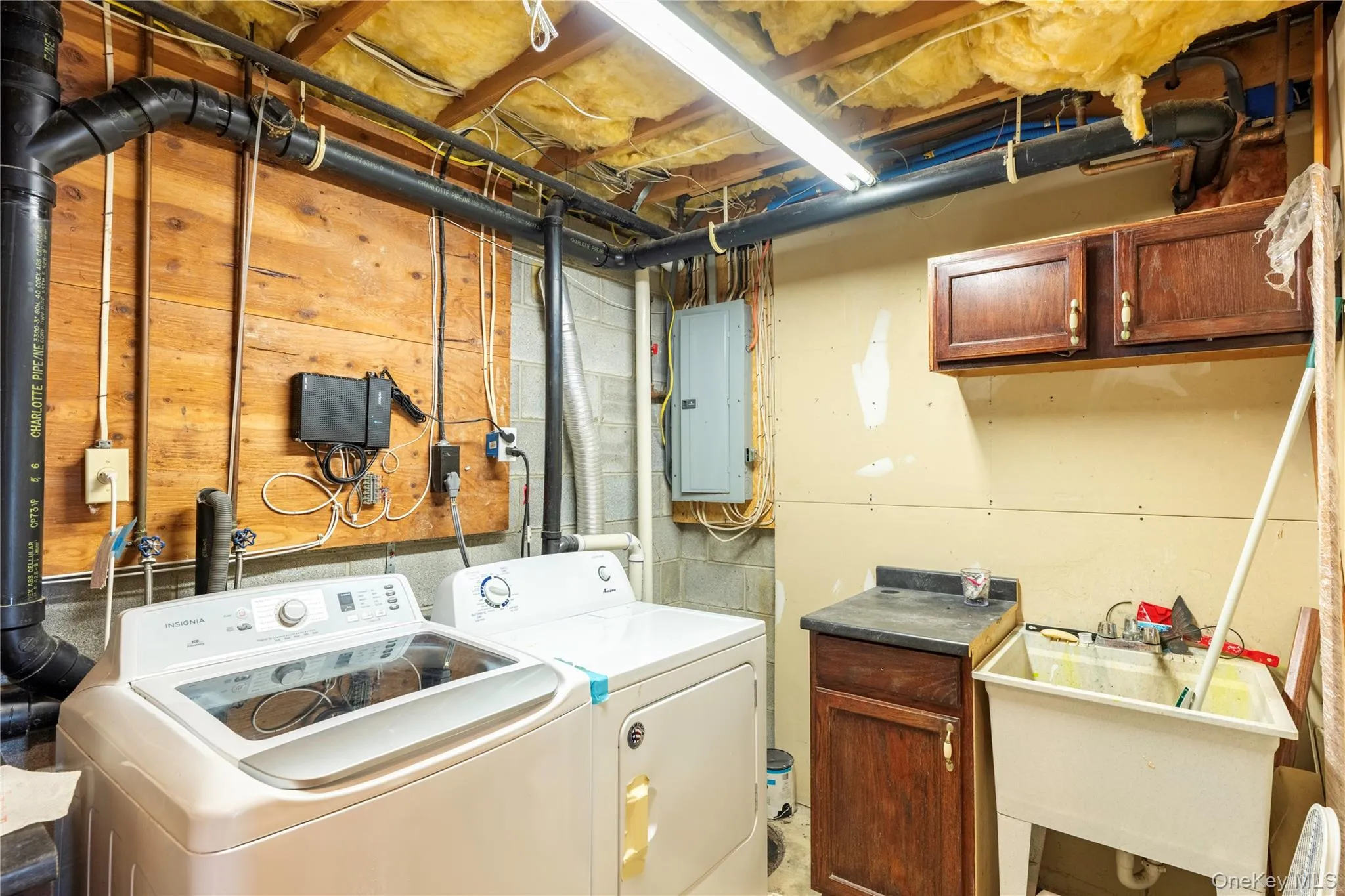 Dedicated utility space featuring exposed ceiling joists with insulation, a utility sink, and wall-mounted cabinetry Dedicated utility space featuring exposed ceiling joists with insulation, a utility sink, and wall-mounted cabinetry