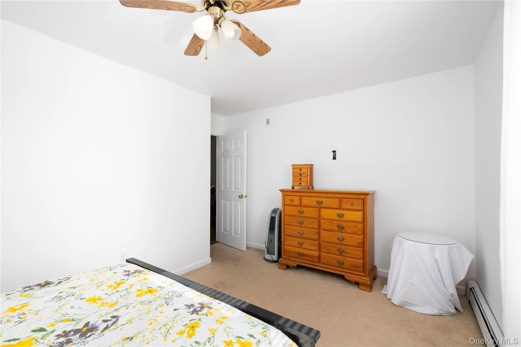 Carpeted room featuring a ceiling fan with light fixture and a white interior door Carpeted room featuring a ceiling fan with light fixture and a white interior door