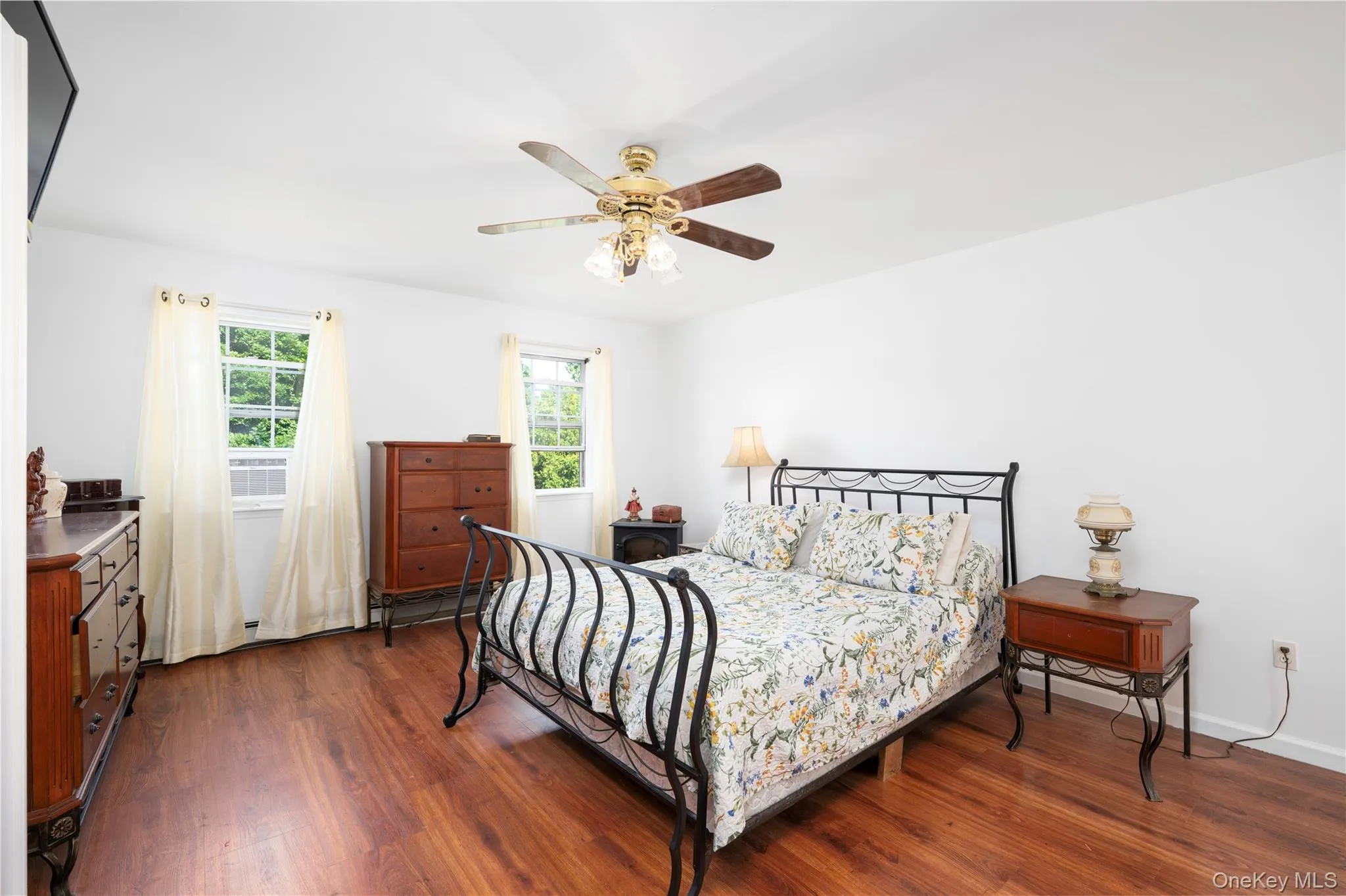 Bright room with wood-finish flooring, white walls, and a ceiling fan with integrated lighting Bright room with wood-finish flooring, white walls, and a ceiling fan with integrated lighting