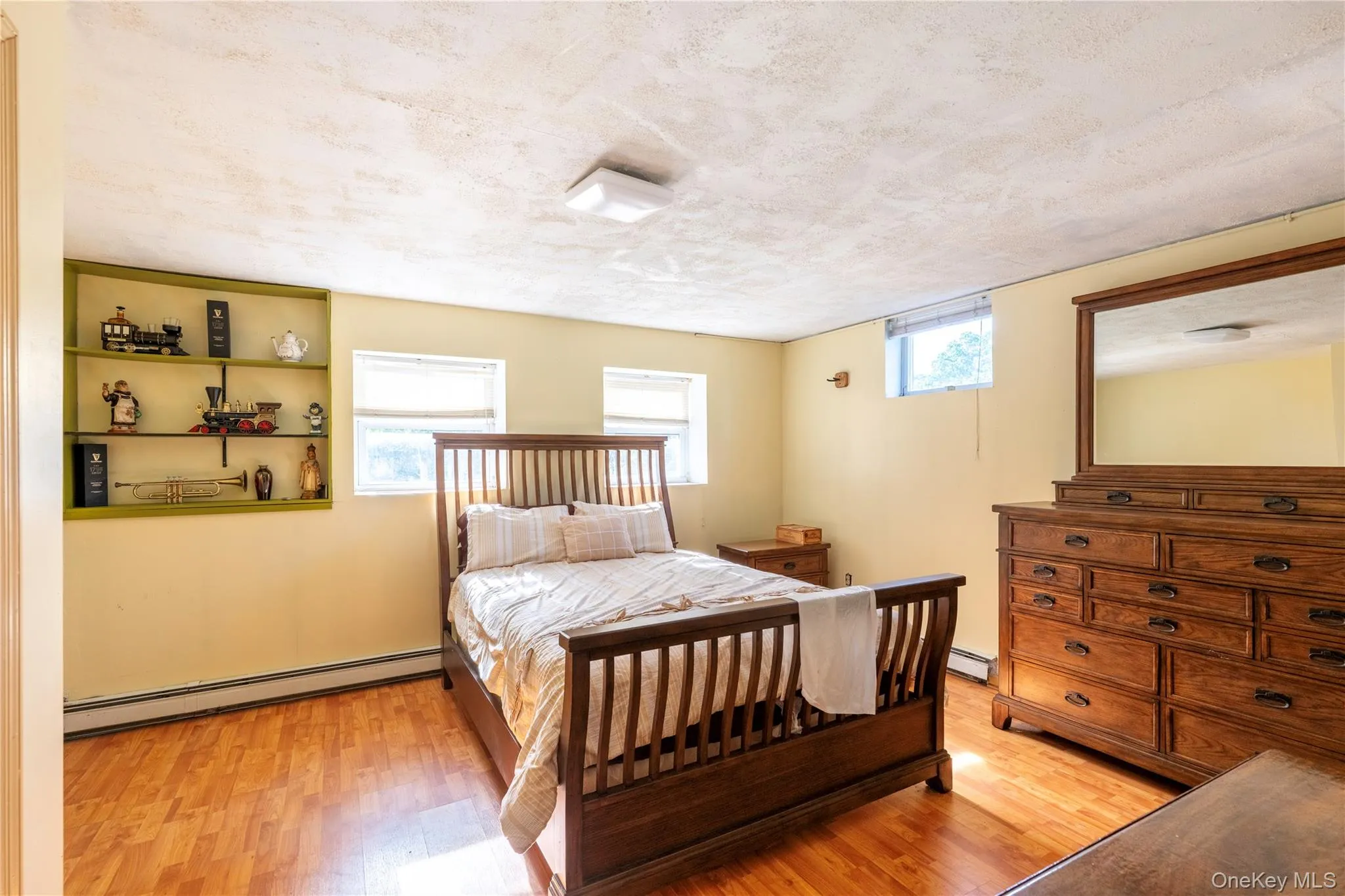 Room featuring wood-finish flooring, multiple windows, and a built-in shelving unit with a distinct green trim Room featuring wood-finish flooring, multiple windows, and a built-in shelving unit with a distinct green trim