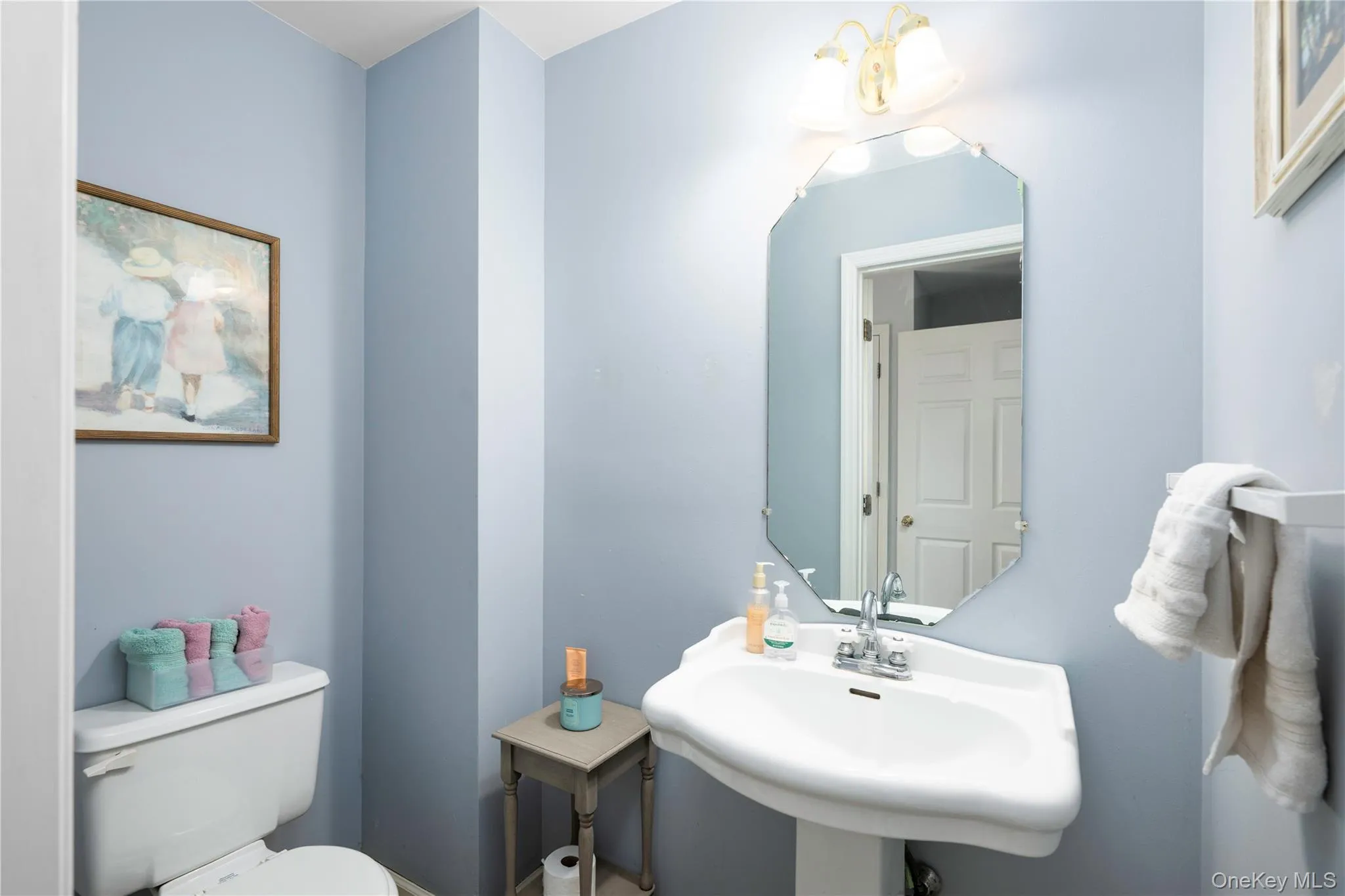 Pedestal sink with chrome faucet, complemented by an octagonal wall mirror Pedestal sink with chrome faucet, complemented by an octagonal wall mirror
