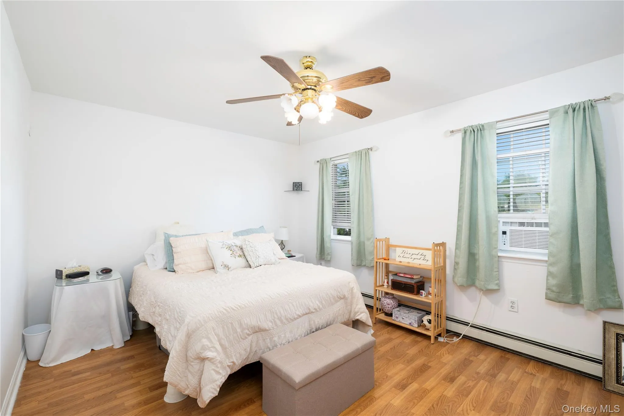 Room featuring wood-finish flooring, two windows with blinds, and an overhead ceiling fan with lighting Room featuring wood-finish flooring, two windows with blinds, and an overhead ceiling fan with lighting