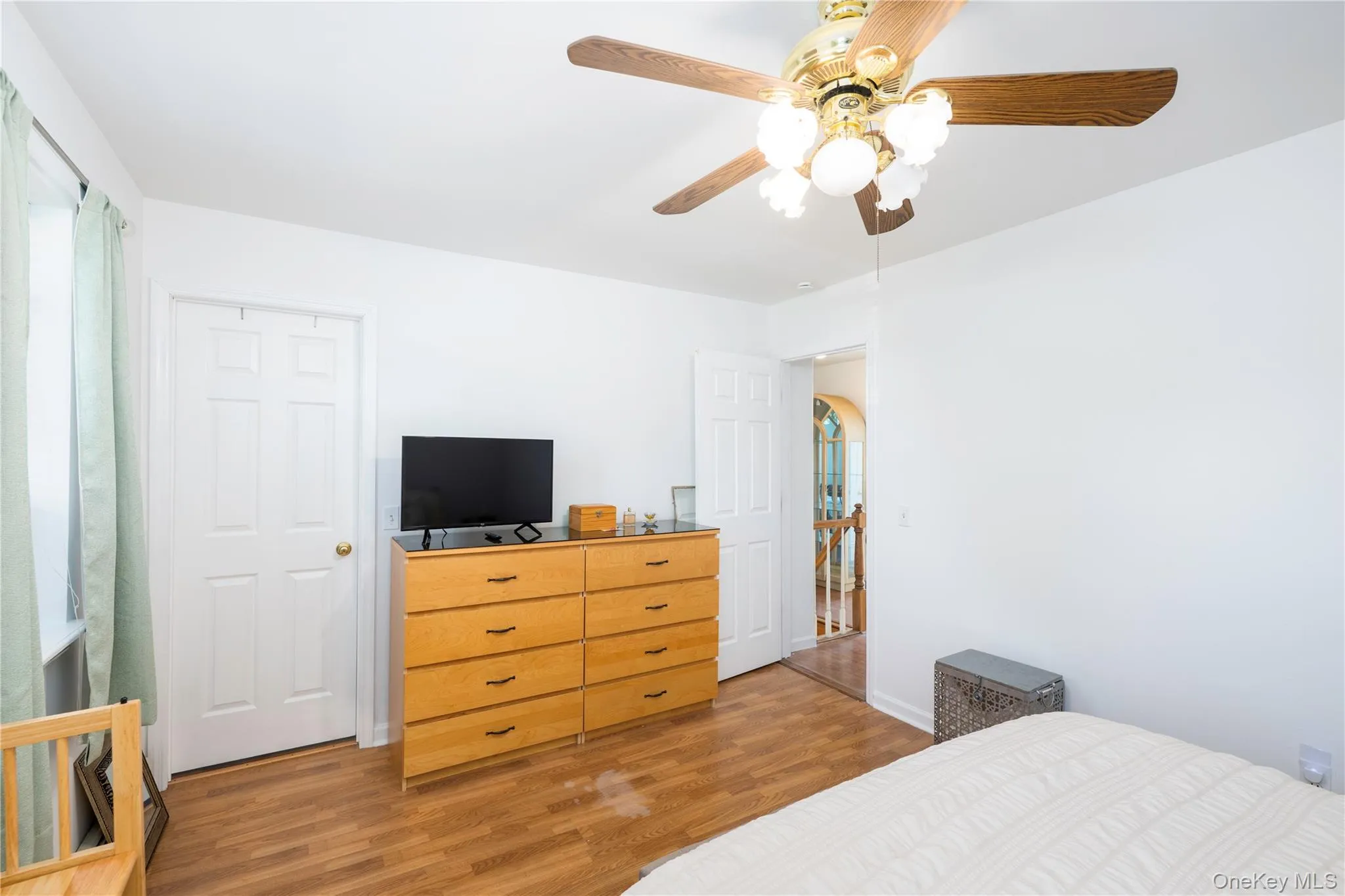 Bedroom featuring wood-finish flooring, a ceiling fan with integrated lighting, and multiple white paneled doors Bedroom featuring wood-finish flooring, a ceiling fan with integrated lighting, and multiple white paneled doors
