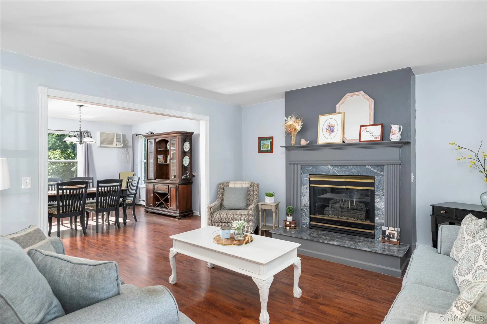 Living area featuring wood-finish flooring and a fireplace with a stone surround and mantel Living area featuring wood-finish flooring and a fireplace with a stone surround and mantel