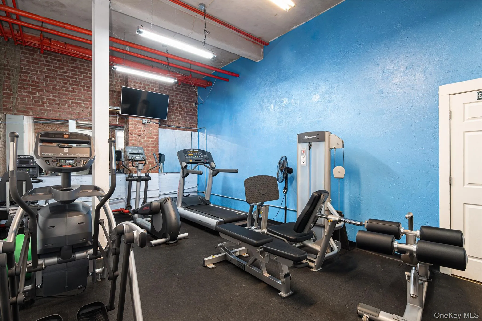 Exercise room featuring brick wall and a high ceiling Exercise room featuring brick wall and a high ceiling