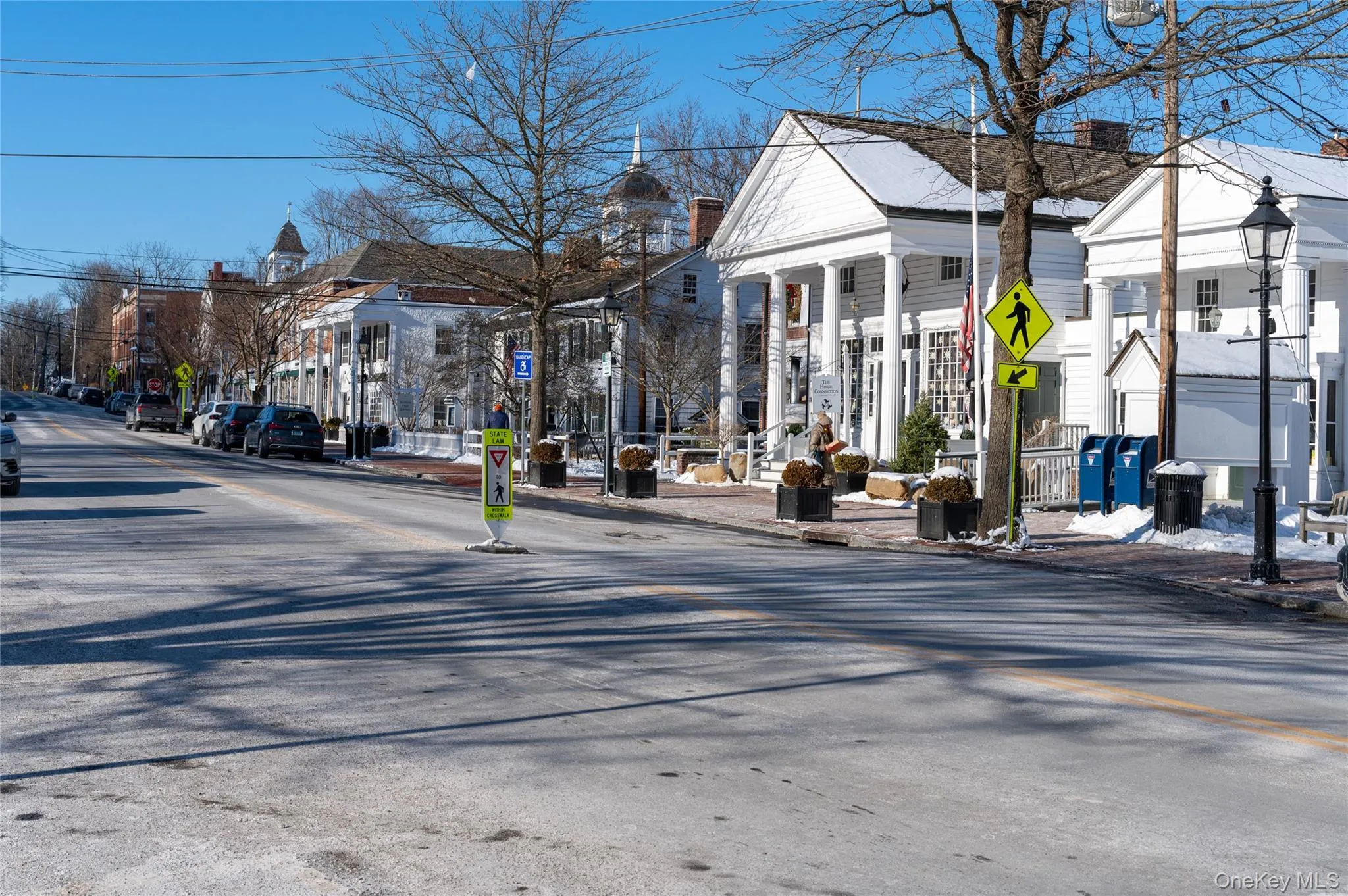 View of asphalt road featuring curbs, street lights, a residential view, and sidewalks View of asphalt road featuring curbs, street lights, a residential view, and sidewalks