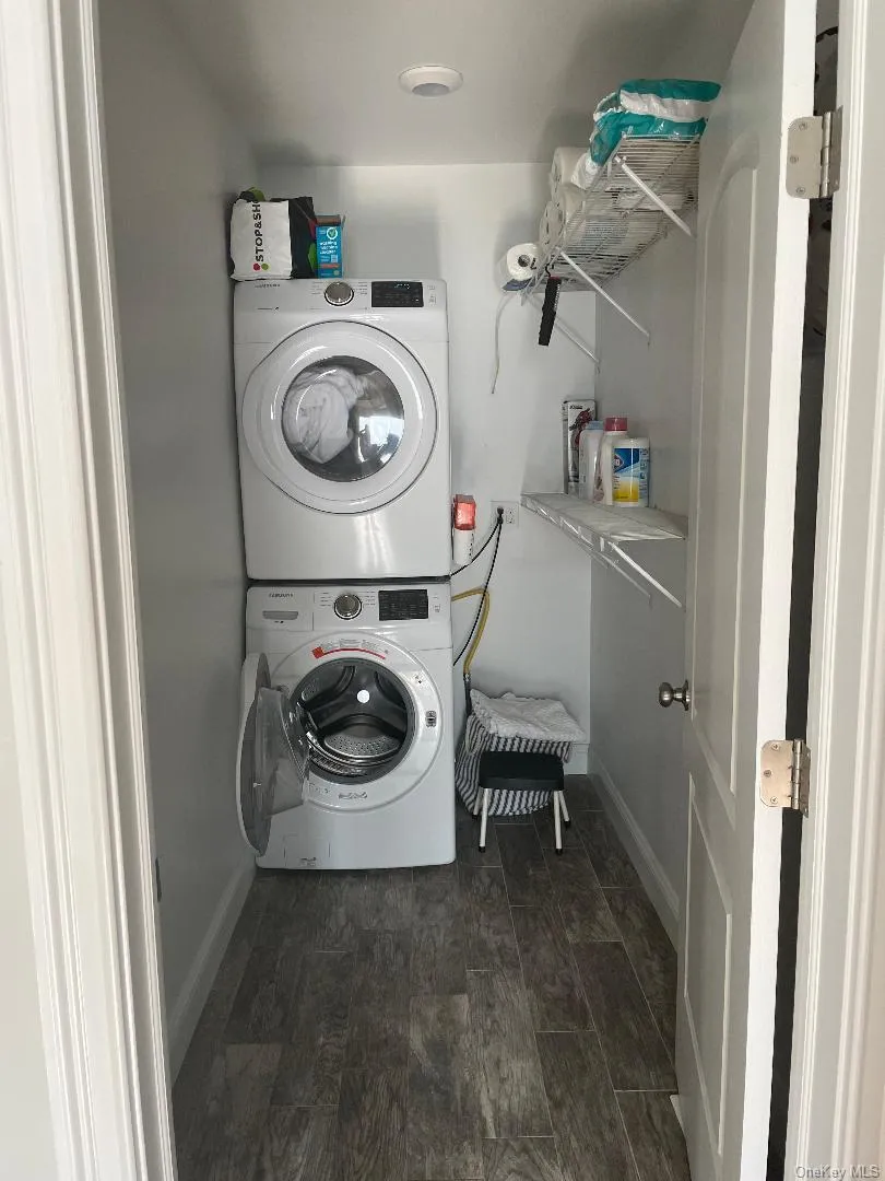 Laundry room with estacked washer and dryer and dark wood finished floors Laundry room with estacked washer and dryer and dark wood finished floors