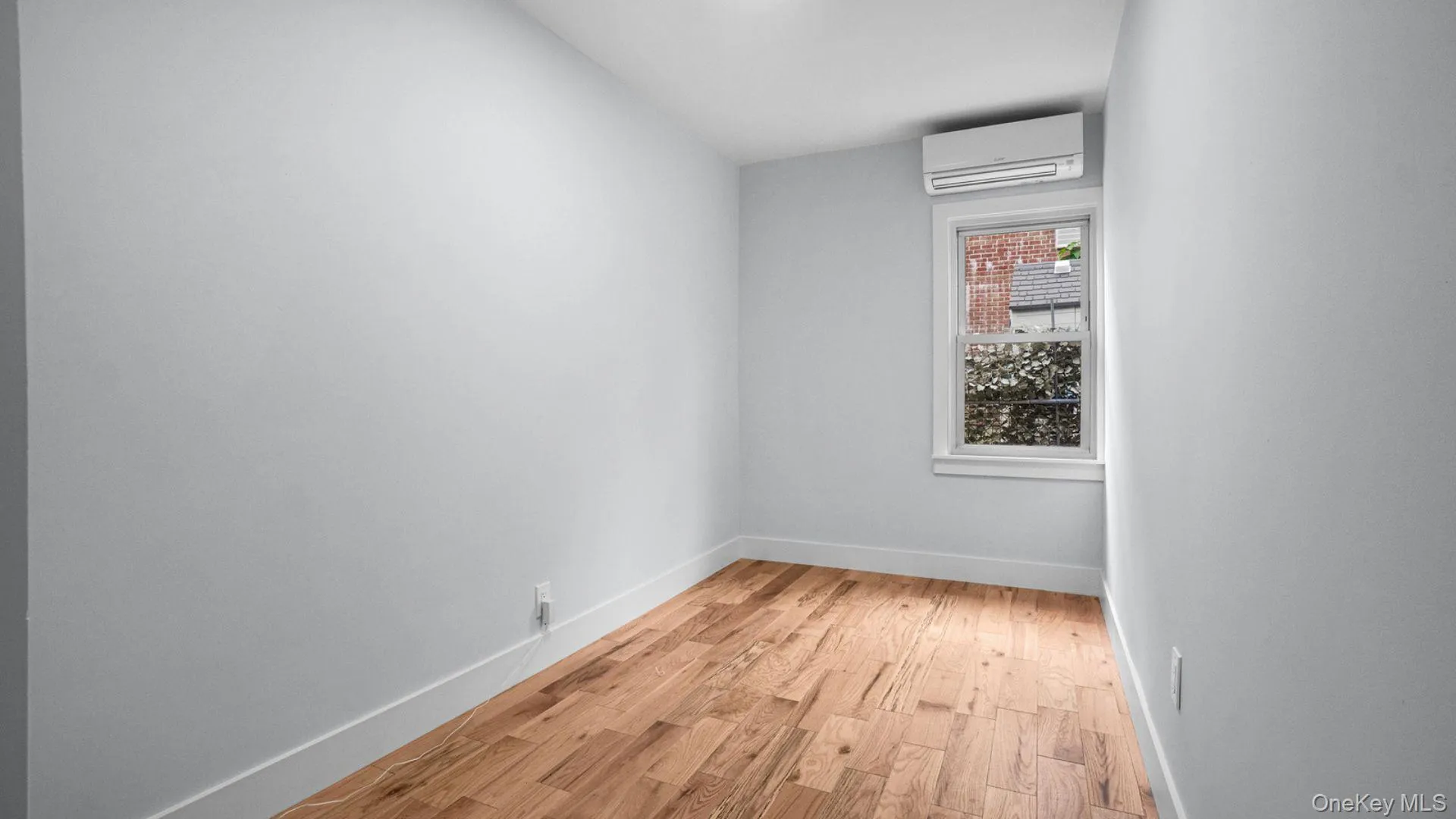 Unfurnished room with light wood-style flooring and an AC wall unit Unfurnished room with light wood-style flooring and an AC wall unit