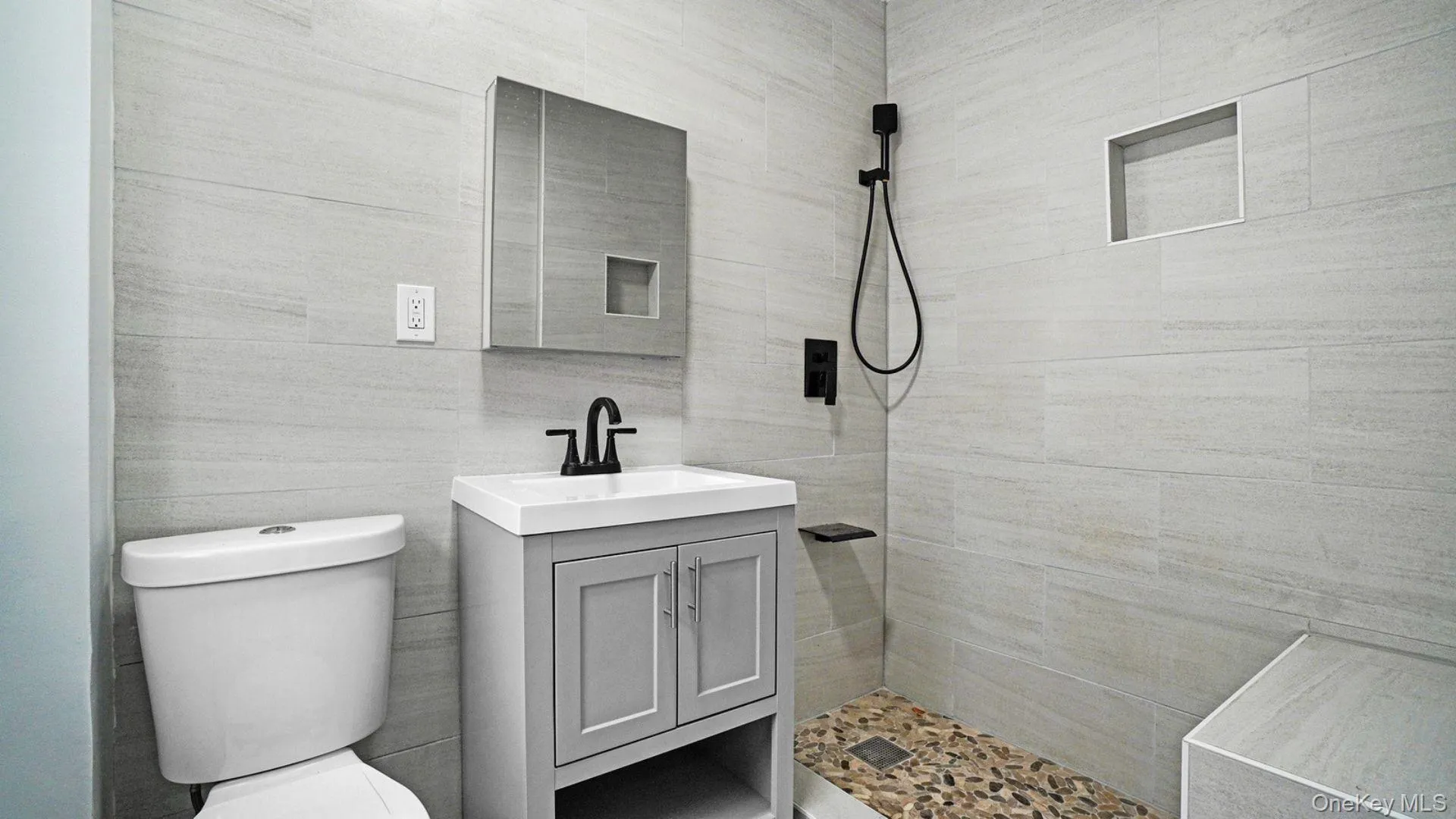 Bathroom featuring vanity, a shower stall, and tile walls Bathroom featuring vanity, a shower stall, and tile walls