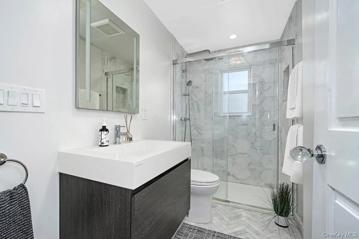 Beautiful hall bath with marble tile on floor and in shower enclosure. Stylish vanity Beautiful hall bath with marble tile on floor and in shower enclosure. Stylish vanity