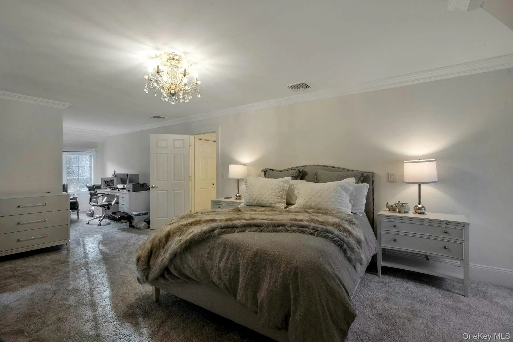 Bedroom with crown molding, a notable chandelier, and dark colored carpet Bedroom with crown molding, a notable chandelier, and dark colored carpet