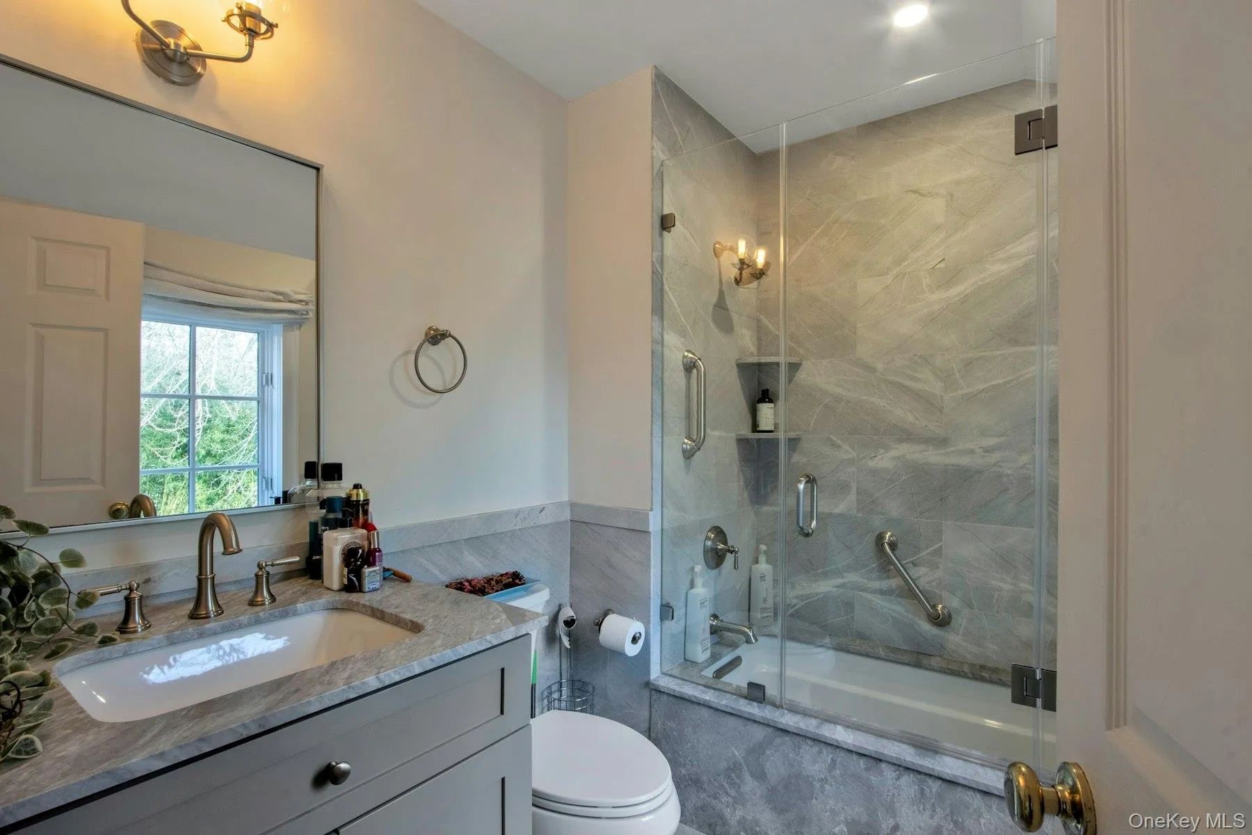 Full bathroom featuring vanity, toilet, and enclosed tub / shower combo Full bathroom featuring vanity, toilet, and enclosed tub / shower combo