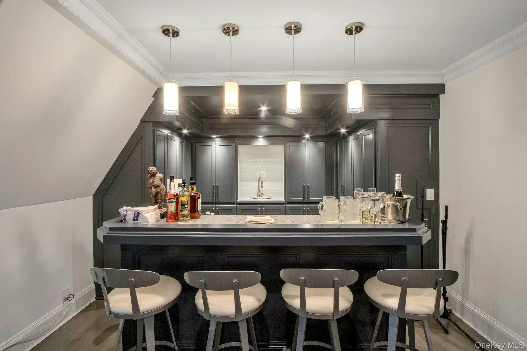 Den Bar with sink, hardwood / wood-style floors, pendant lighting, and ornamental molding Den Bar with sink, hardwood / wood-style floors, pendant lighting, and ornamental molding